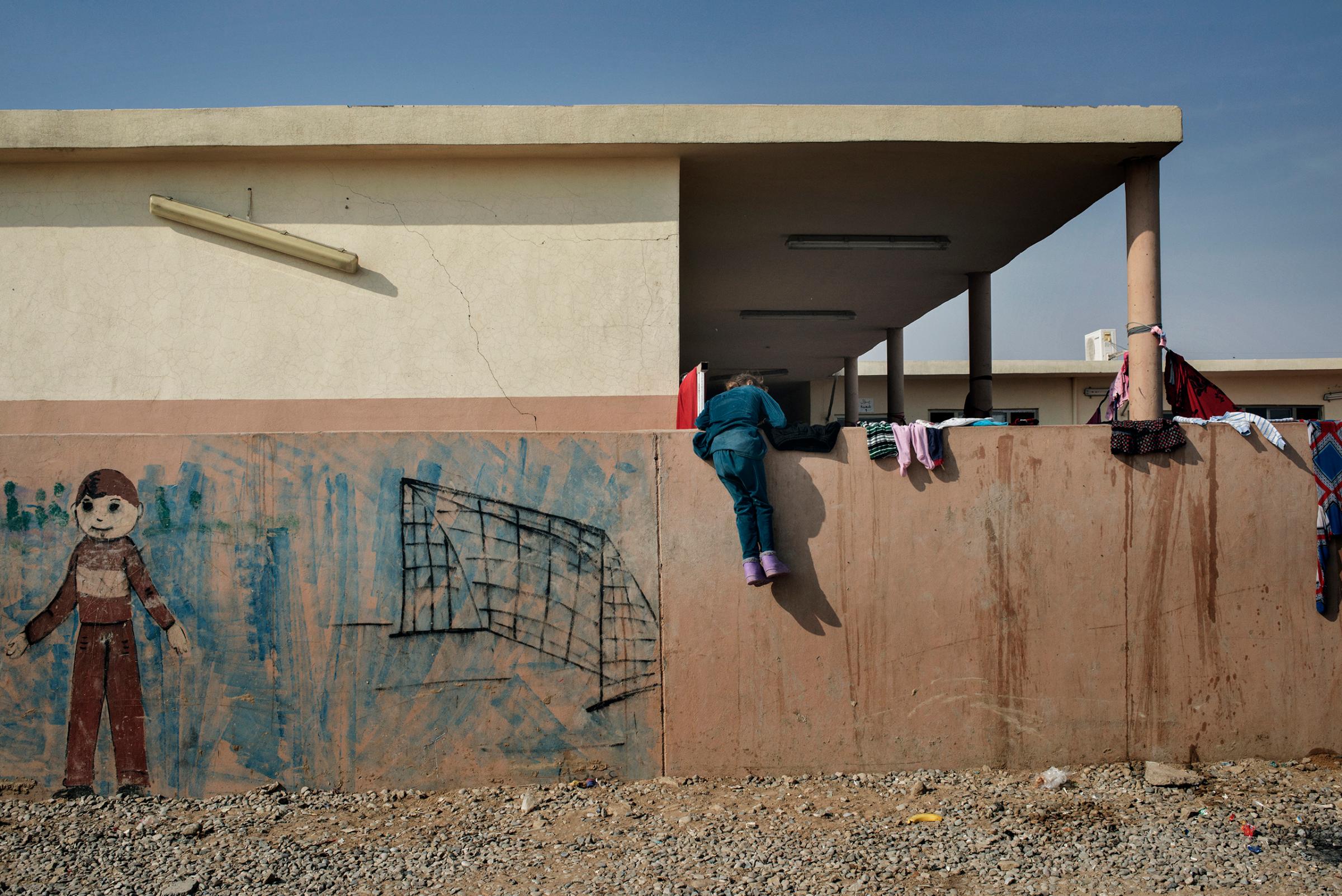 A girl climbs on a wall inside the Debaga refugee camp in northern Iraq. Aid organizations are preparing for a mass of refugees to pour out of Mosul.