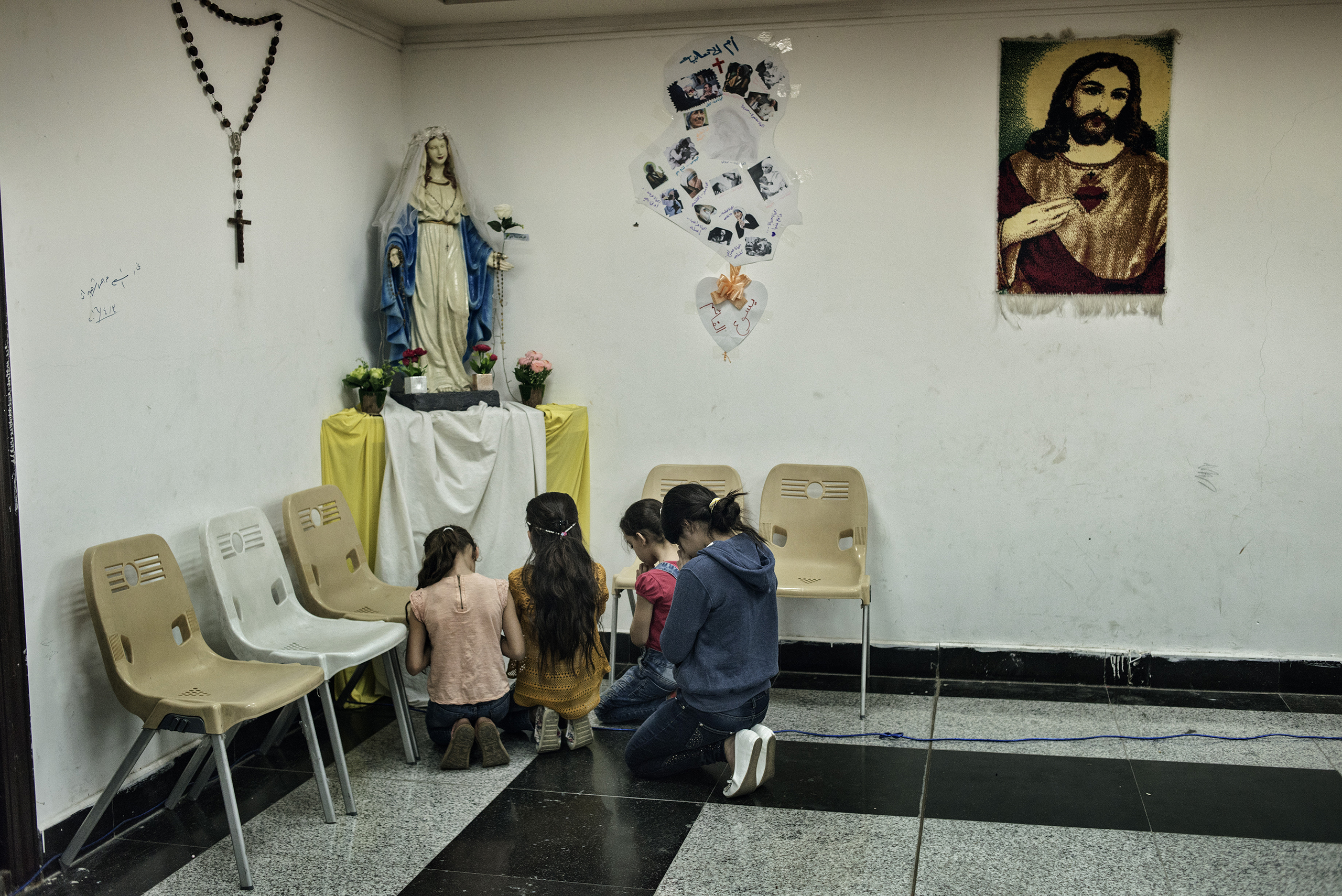 Girls pray after Sunday Mass inside a shopping mall in Erbil where many Christian families from Bartella and Qaraqosh moved to live after ISIS seized their cities two years ago.
