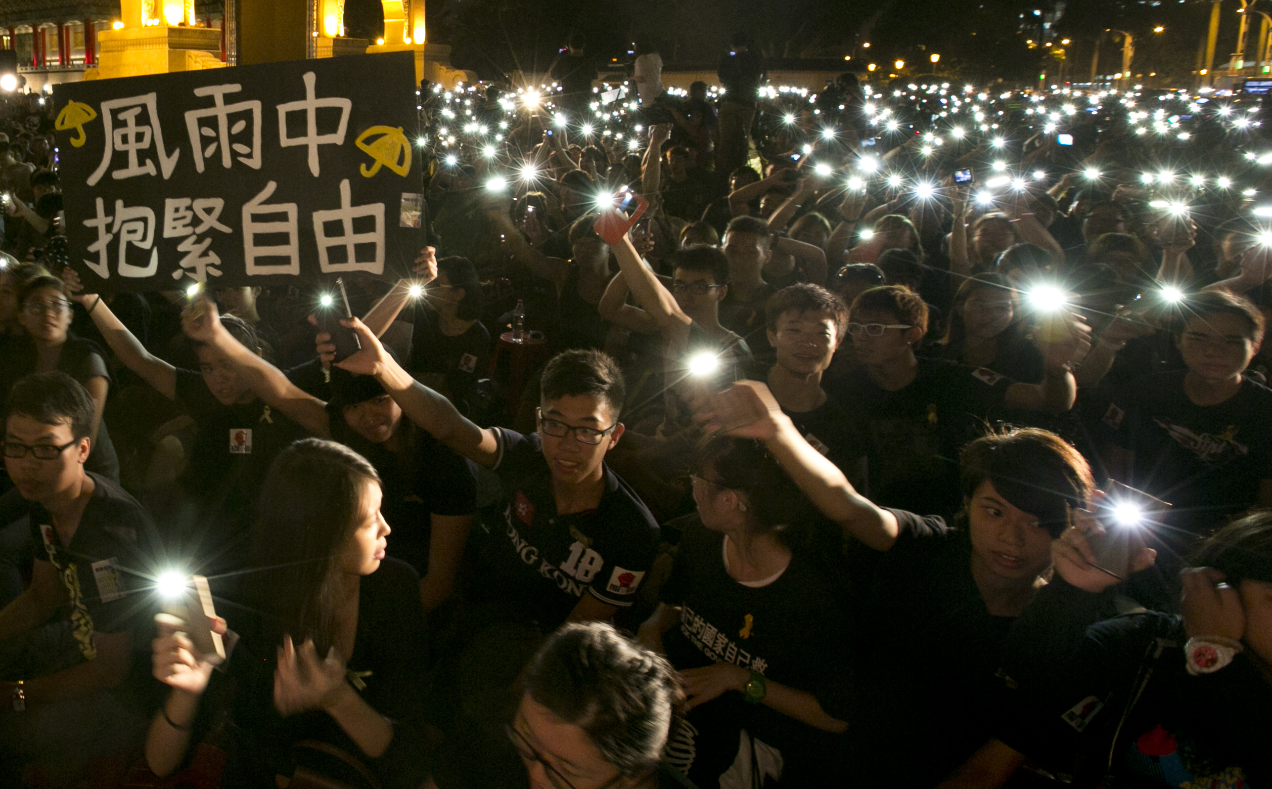 Hundreds of Taiwanese students raise their cell phones with one sign reading "Hold On to Freedom in the Rain" on Oct. 1, 2014, in front of Liberty Square in Taipei to show support for Hong Kong pro-democracy rallies (Ashley Pon—Getty Images)