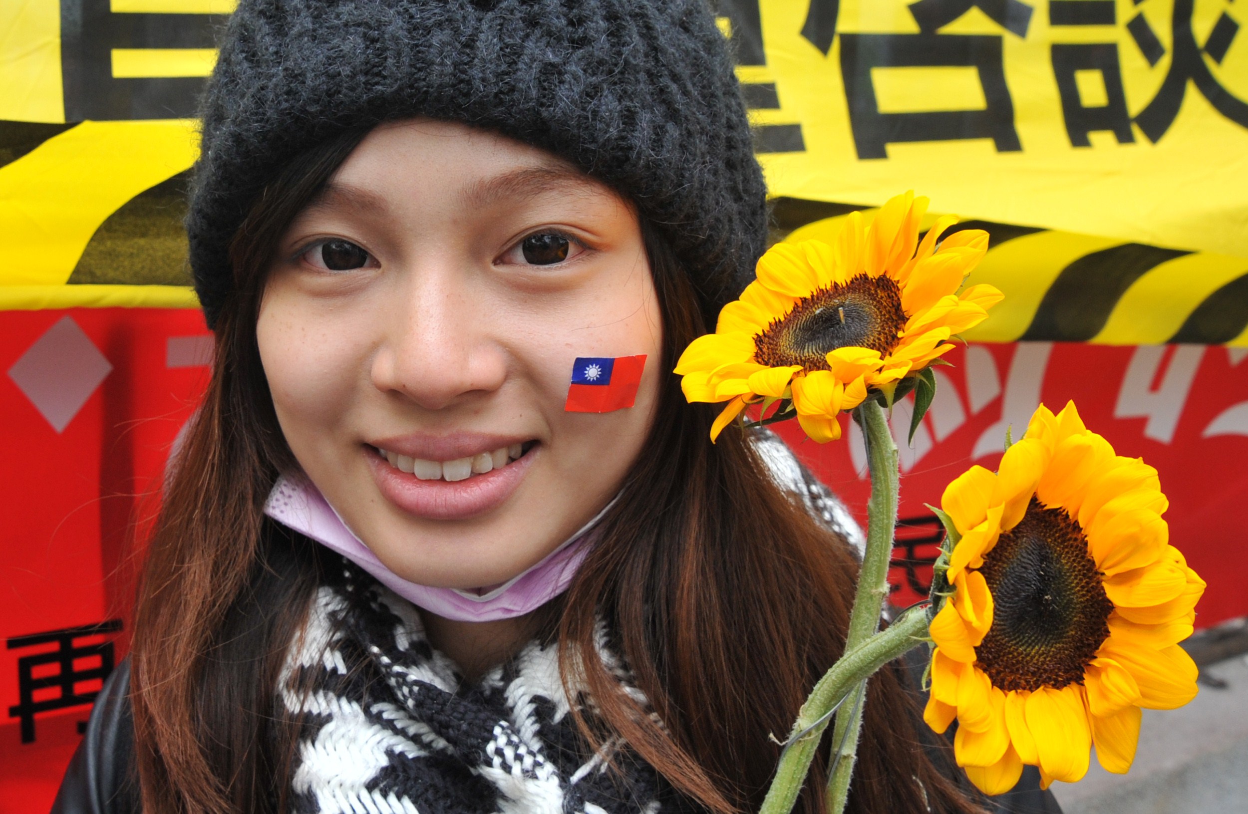 An activist holds sunflowers and wears a sticker of Taiwan's national flag on her face in support of student protesters occupying the parliament building in Taipei on March 21, 2014 (AFP/Getty Images)