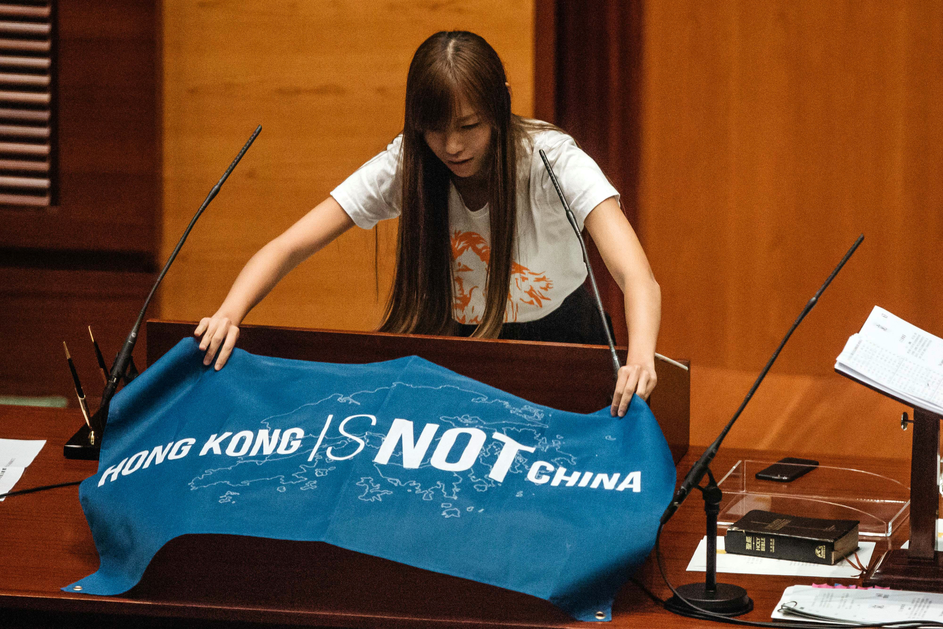 Yau Wai-ching, an incoming lawmaker and member of Youngspiration, unfurls a banner that reads "Hong Kong Is Not China" in the chamber of the Legislative Council in Hong Kong on Oct. 12, 2016 (Anthony Kwan—Bloomberg/Getty Images)