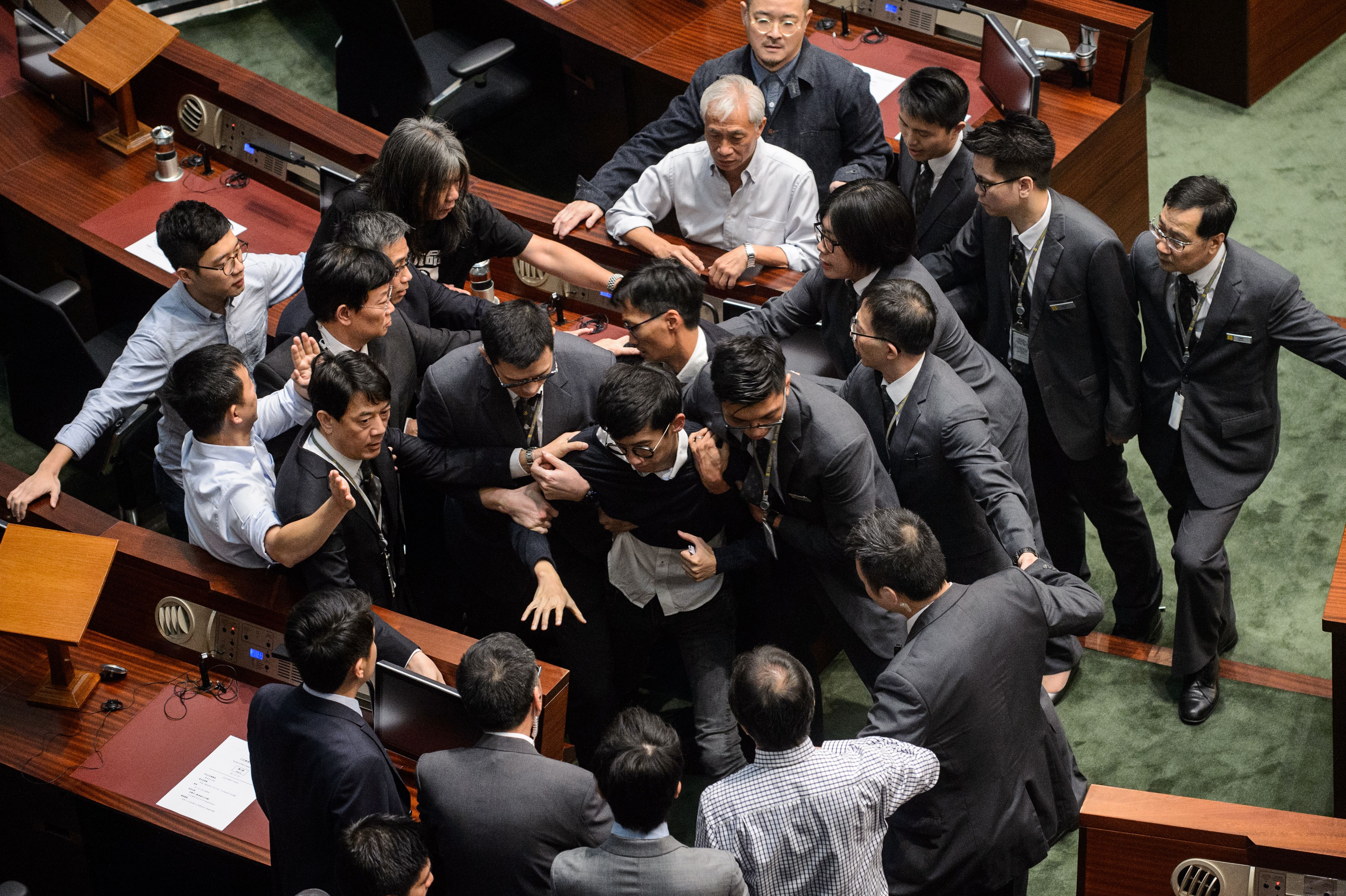 Newly elected lawmaker Sixtus "Baggio" Leung, center, is restrained by security after attempting to read out his oath of office at the Legislative Council in Hong Kong on Nov. 2, 2016 (Anthony Wallace—AFP/Getty Images)