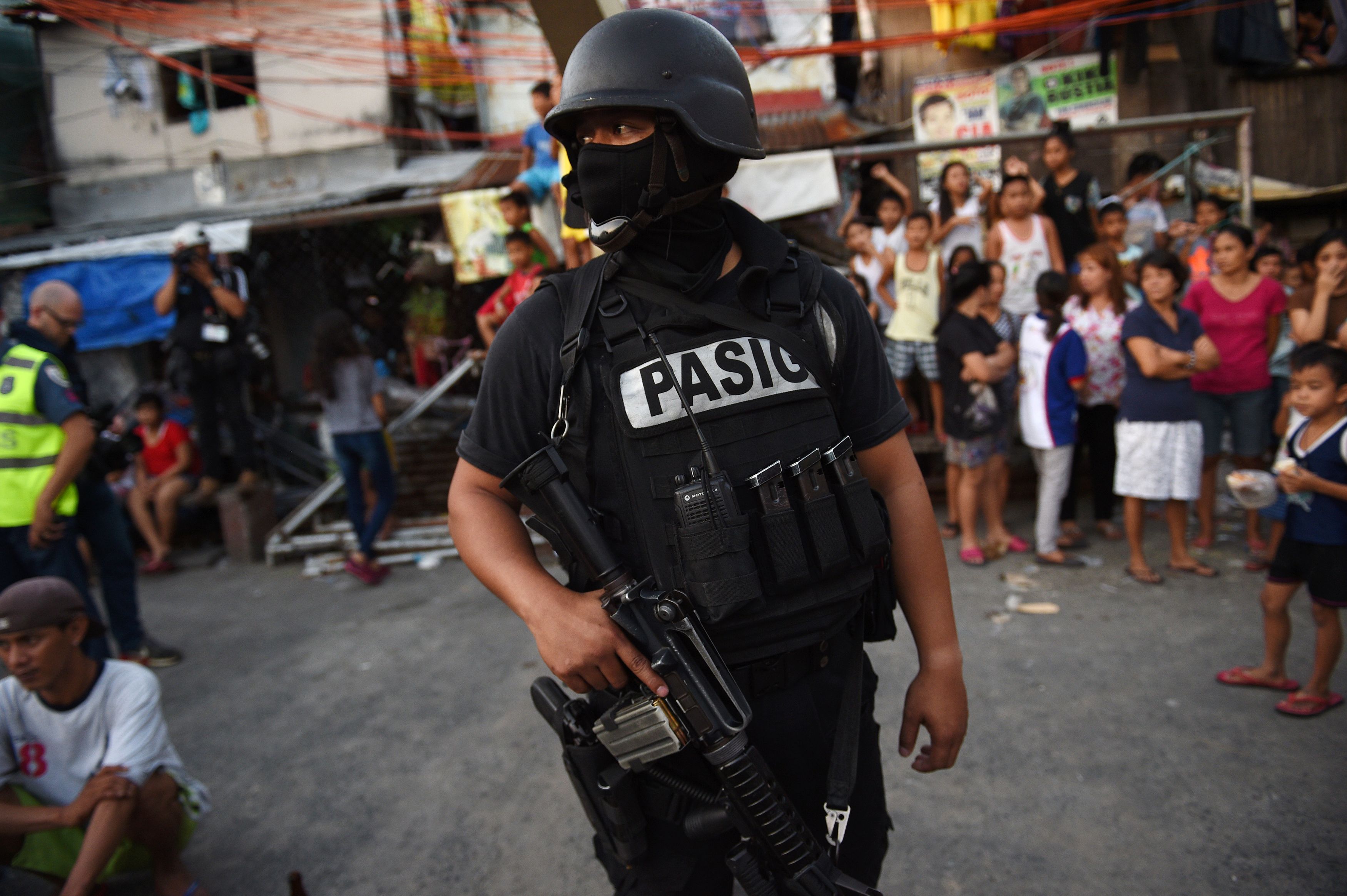A member of the Special Weapons and Tactics (SWAT) team stands guard while residents look on during an antidrug operation at an informal settlers area in Manila on Nov. 9, 2016. Since President Rodrigo Duterte took office on June 30, his war on drugs and other crimes have claimed more than 4,100 lives, according to official figures (Ted Aljibe—AFP/Getty Images)