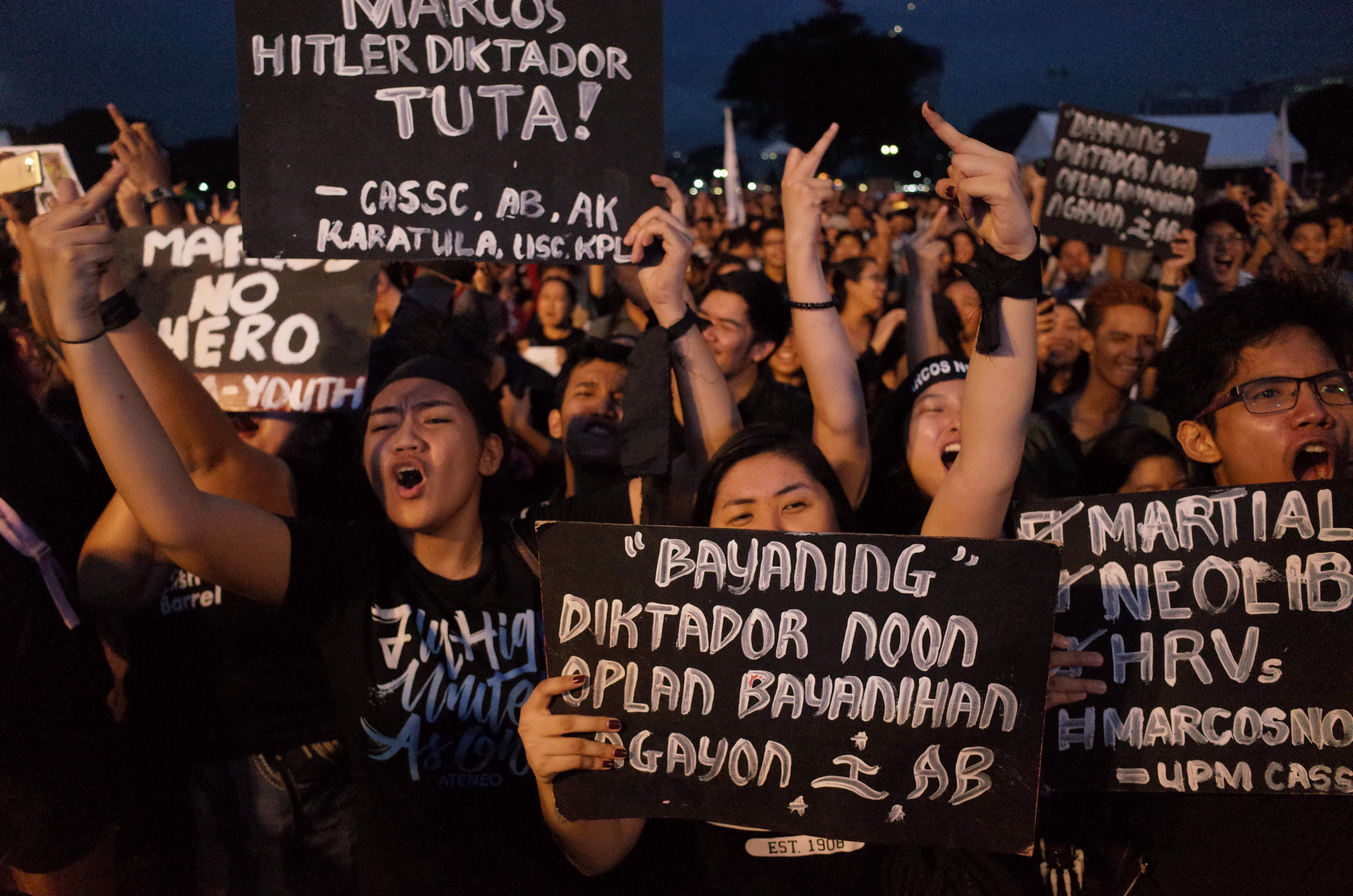 Filipino activists holding placards react to a speaker