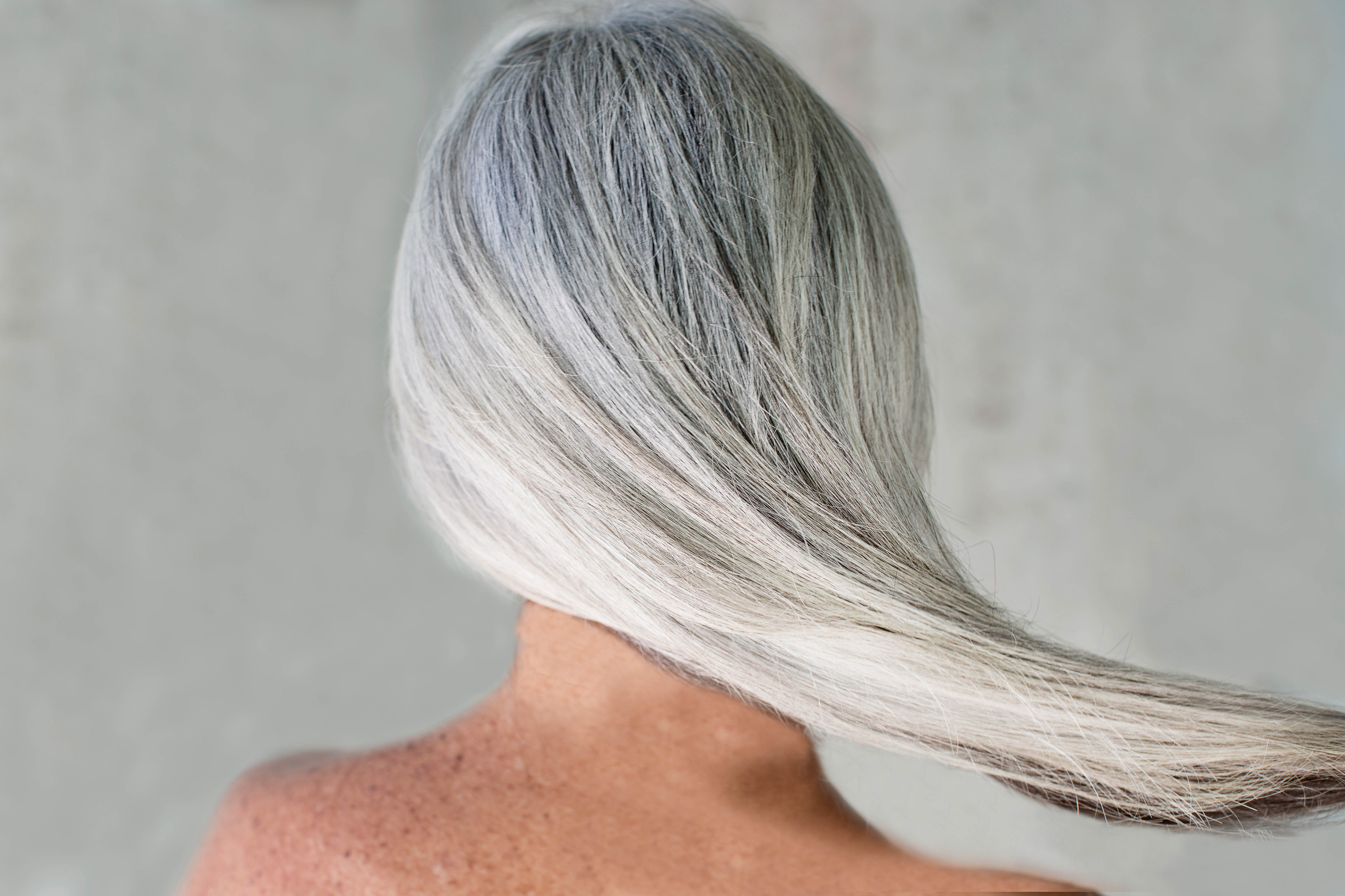 Rear view of bare shouldered mature woman with long grey hair