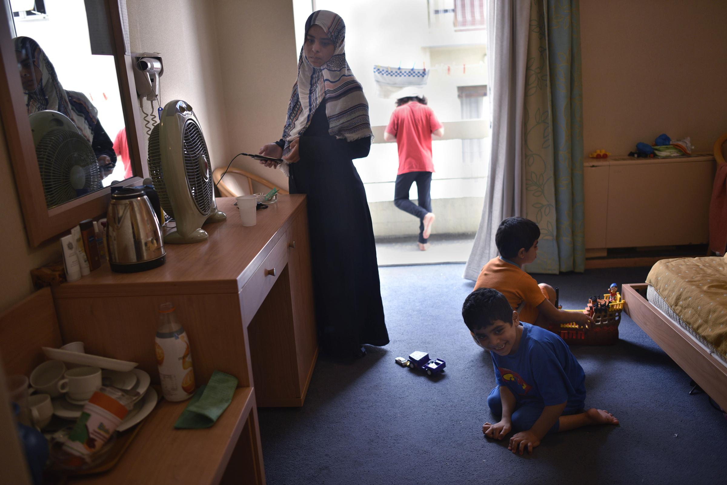 Baida, 27, from Raqqa, Syria, keeps an eye on her three children as they play in her family’s room at the hotel. Her youngest son, 7-year-old Ahmed, has cerebral palsy and cannot walk. He has a wheelchair, but because the elevators are not working in the eight-floor building, the family keeps the wheelchair downstairs in the lobby.