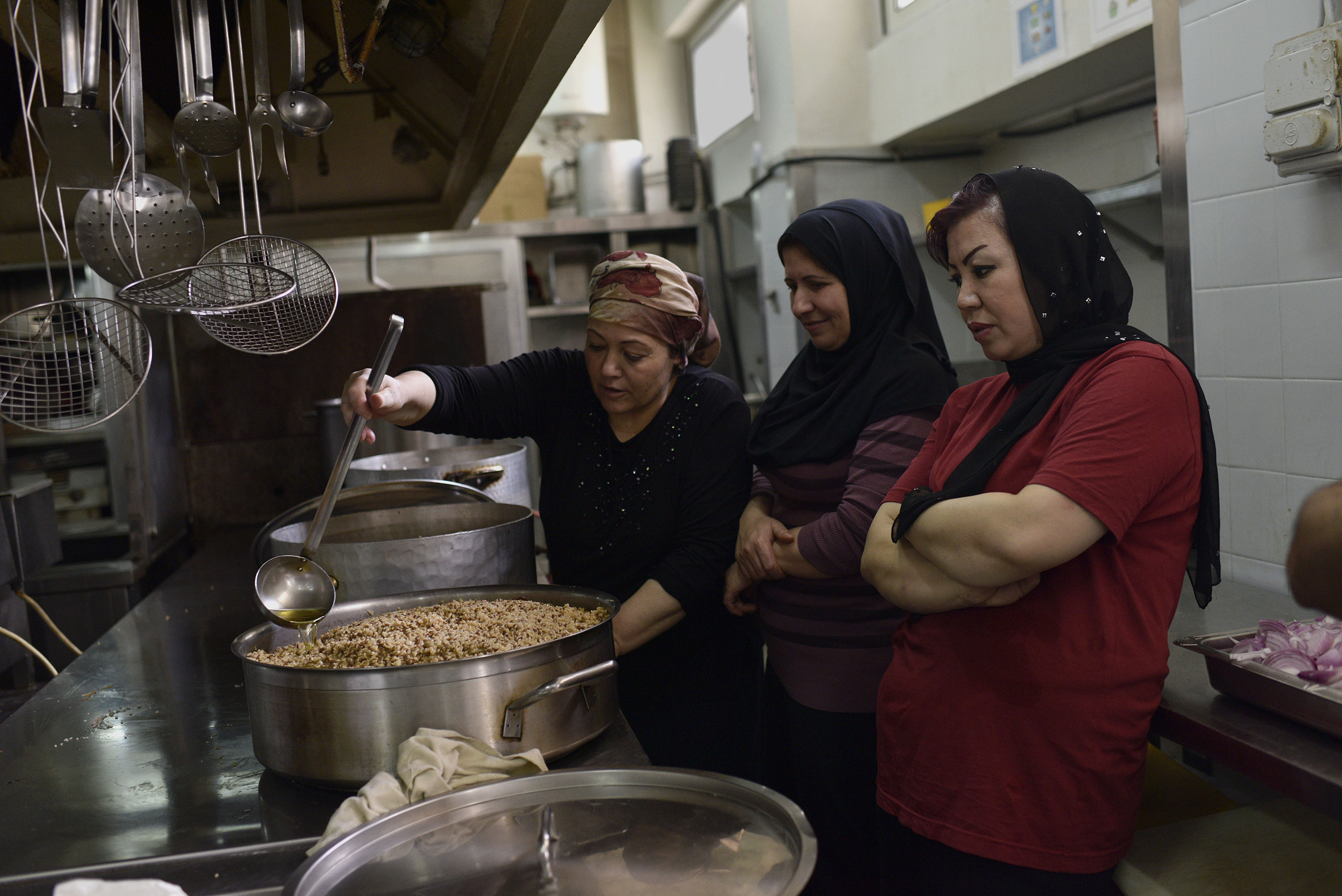Women who made it out of some of the world's worst conflicts, like Syria and Afghanistan, cook alongside one another in the industrial kitchen of the City Plaza hotel. (Lynsey Addario—Getty Images Reportage for TIME)