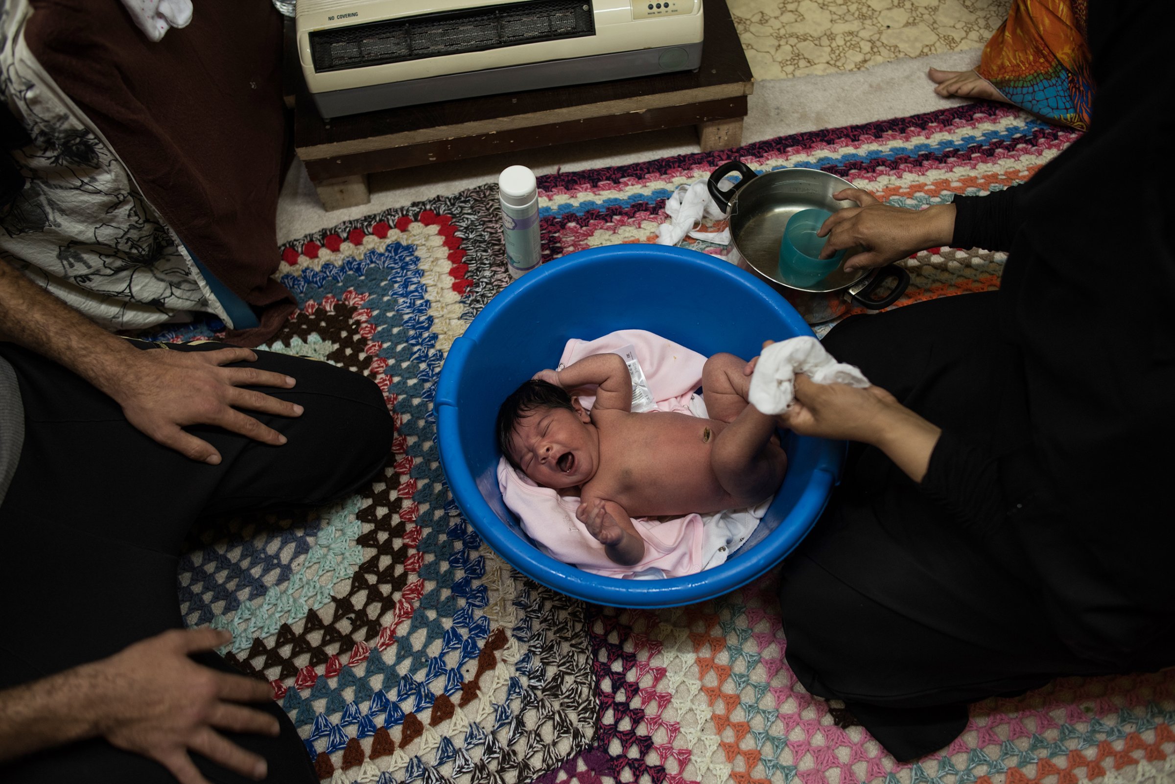 Syrian refugee Hayat bathes baby Rahaf, born one week earlier, next to a heater, at the Oreokastro camp in Thessaloniki, Greece, on Nov. 8, 2016. Rahaf was born to Noor Alhouda Talaa, 22, and Yusuf Arsan, 27.