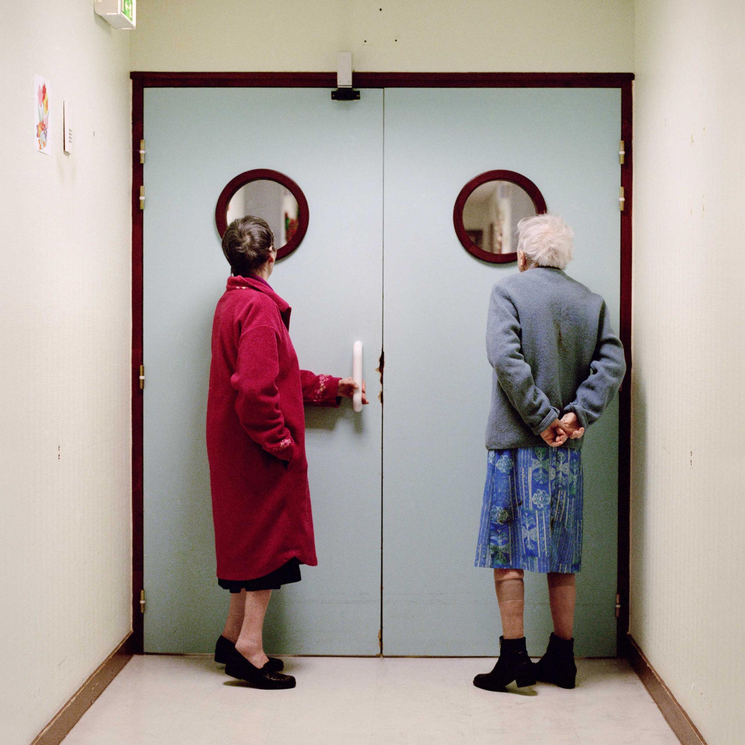 Two residents stand in front of the ward’s locked exit door