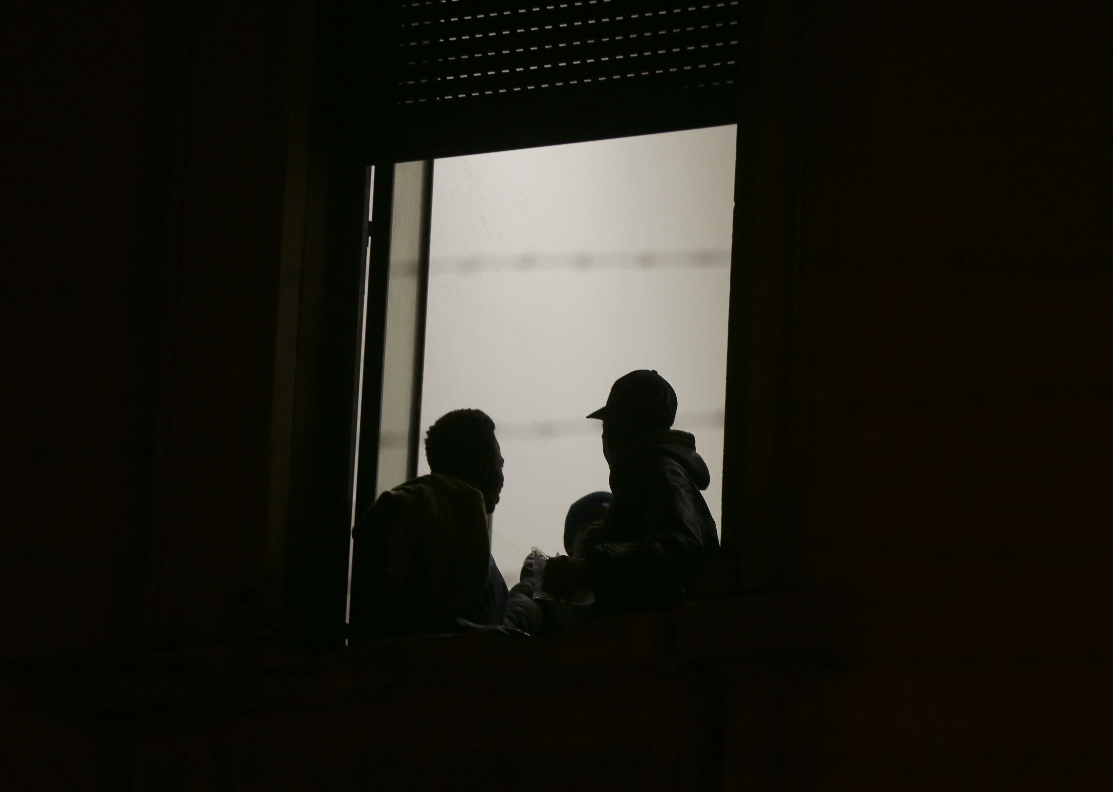 Migrants stand behind a window at the former Montello barrack in Milan, Italy, on Oct. 31, 2016. (Luca Bruno—AP)