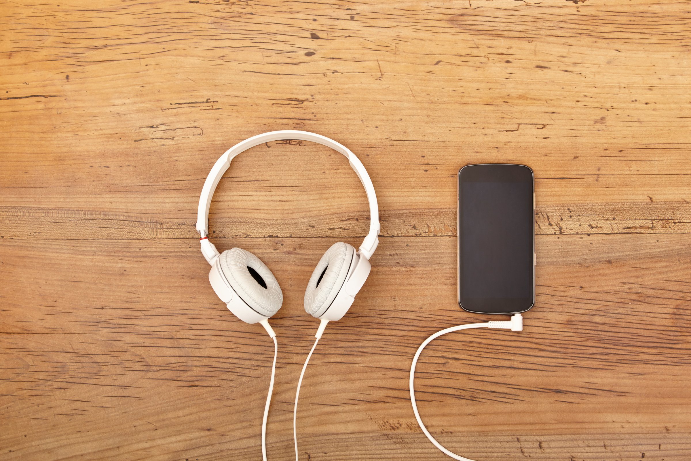 White headphones and smart phone on wood