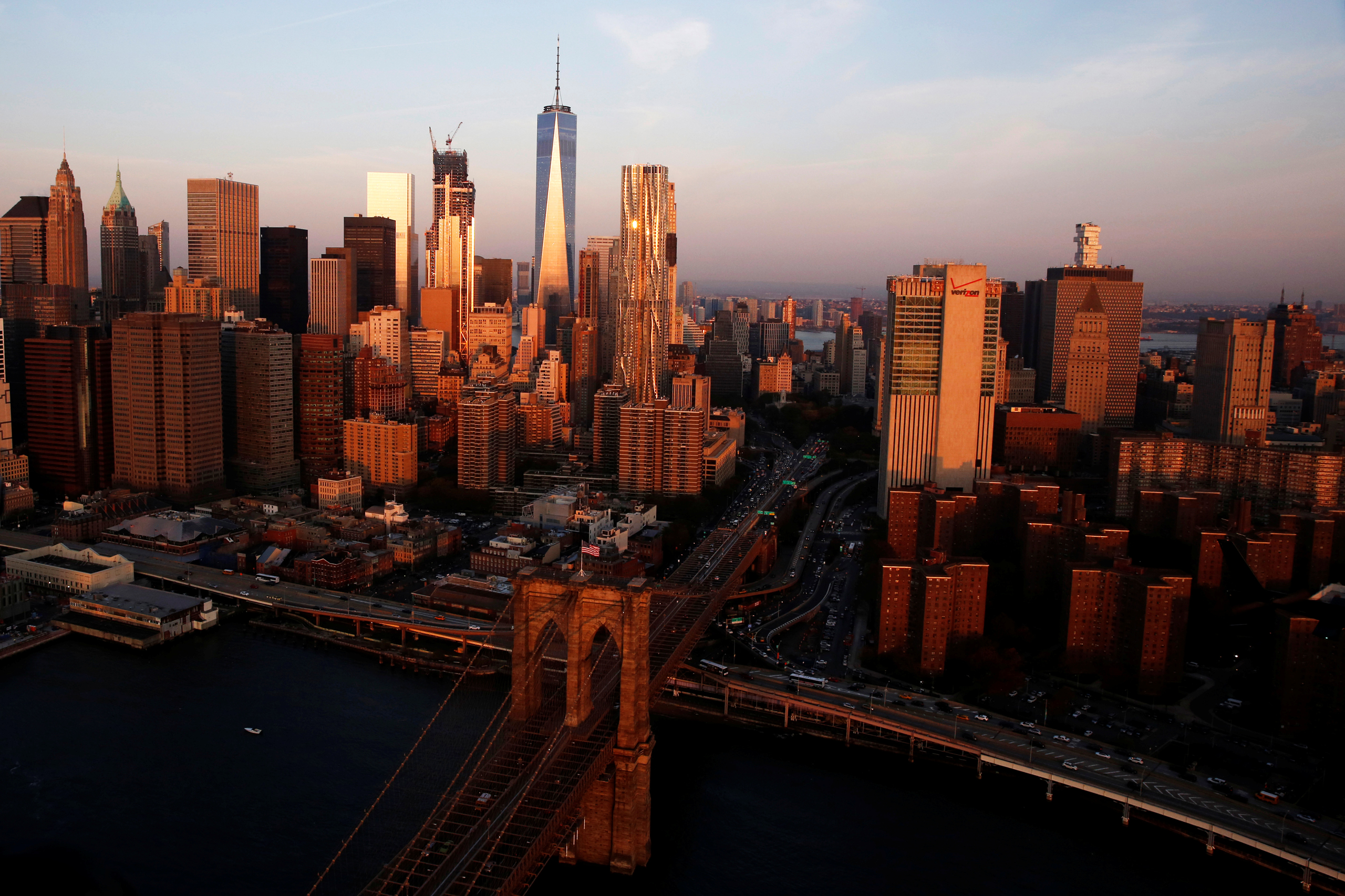 The rising sun lights the Brooklyn Bridge and One World Trade in the Manhattan borough of New York