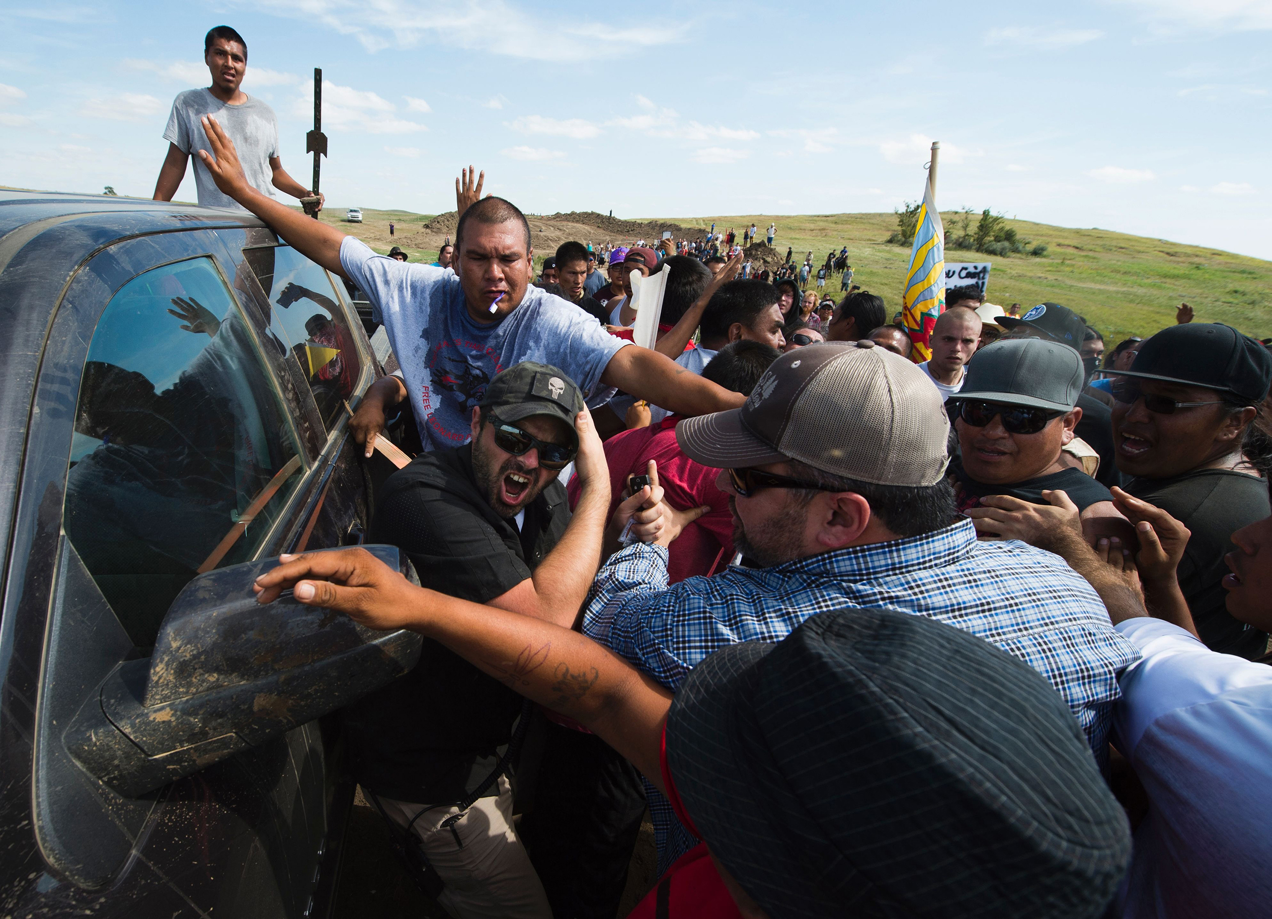 Protesters protect a security contractor from other protesters 
                      on Sept. 3 (ROBYN BECK—AFP/Getty Images)