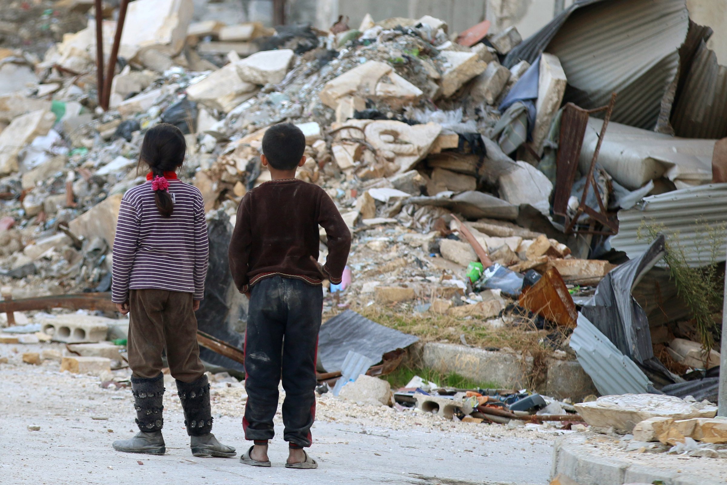 Children inspect rubble of damaged buildings in a rebel-held besieged area in Aleppo