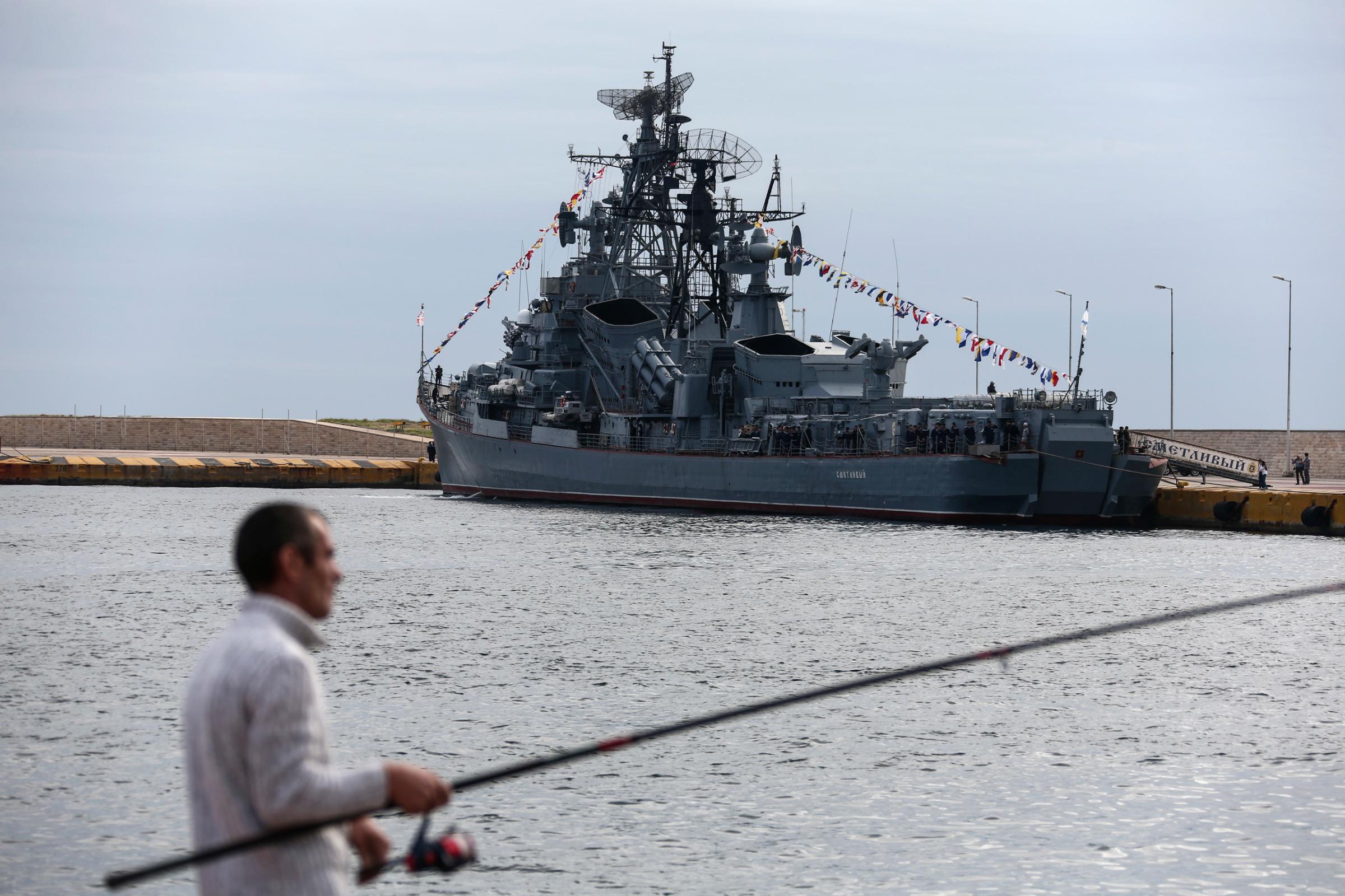 A man fishes near to the Russian Navy missile destroyer Smetlivy, moored at a pier in Piraeus port, near Athens, Sunday, Oct. 30, 2016. The ship left the Crimean port of Sevastopol on Friday and will remain for two days in Piraeus helping to mark the series of cultural and scientific exchange events called "Russia-Greece Year", before joining Russia's battle group on its way to Syria.(AP Photo/Yorgos Karahalis)