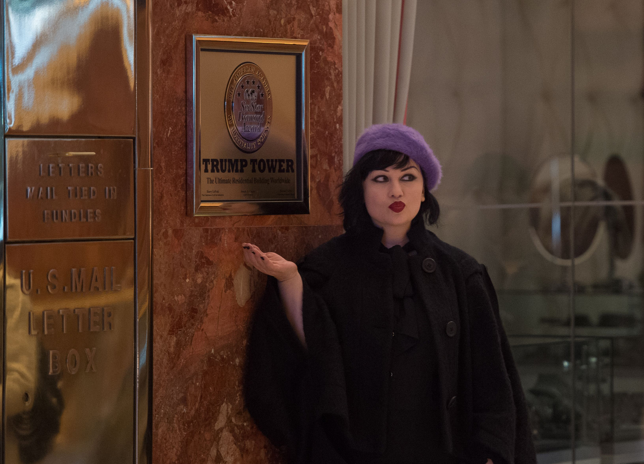 A woman poses near a sign at Trump Tower on Nov. 13, 2016.
