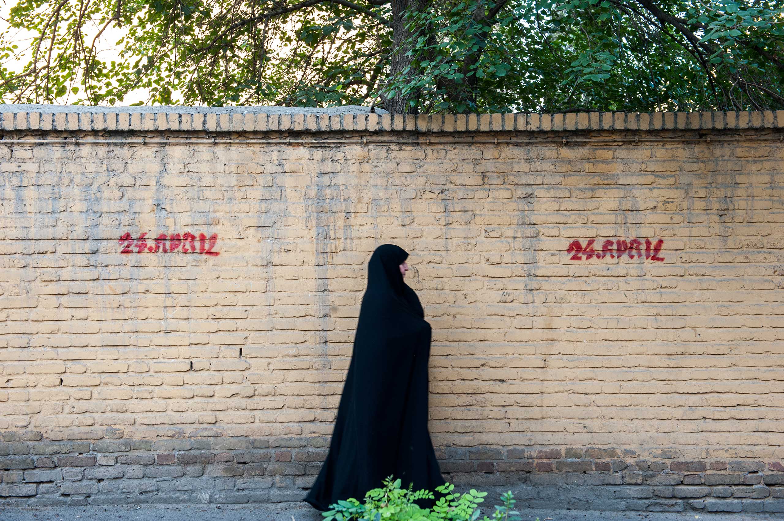 A woman walks by graffiti that reads '24 April 1915' which is date the Armenian genocide began during the Ottoman empire. Such graffiti is common in Armenian neighborhoods.