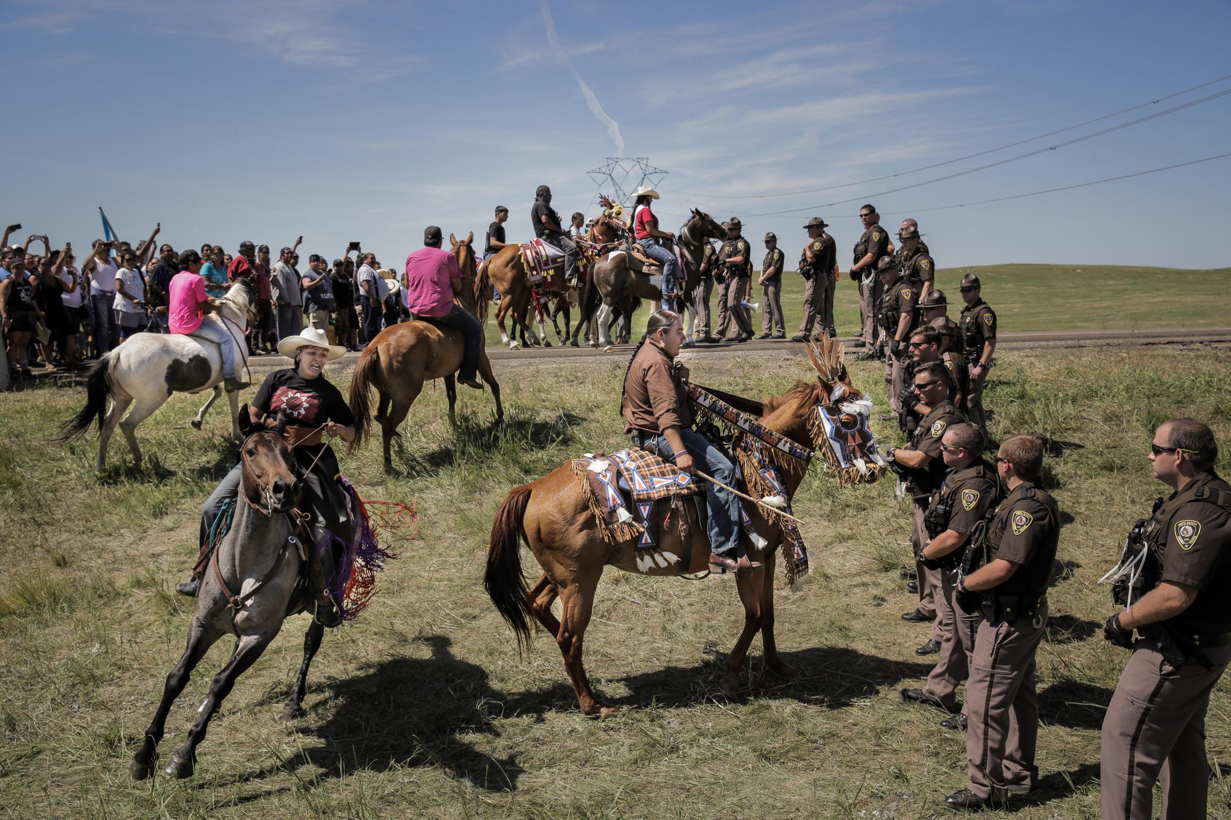 Lakota riders Alex Romero-Frederick (left) and Greg Grey Cloud (right) confront a line of North Dakota State Police the day that construction crews began work on the Dakota Access Pipeline just outside of the Standing Rock Reservation, on Aug. 15, 2016. While the riders did push the police line back after a tense standoff, the display was part of a ceremonial horse introduction meant to be peaceful. For the Standing Rock Lakota, the pipeline represents a major environmental and cultural threat, as well as a violation of treaty land.