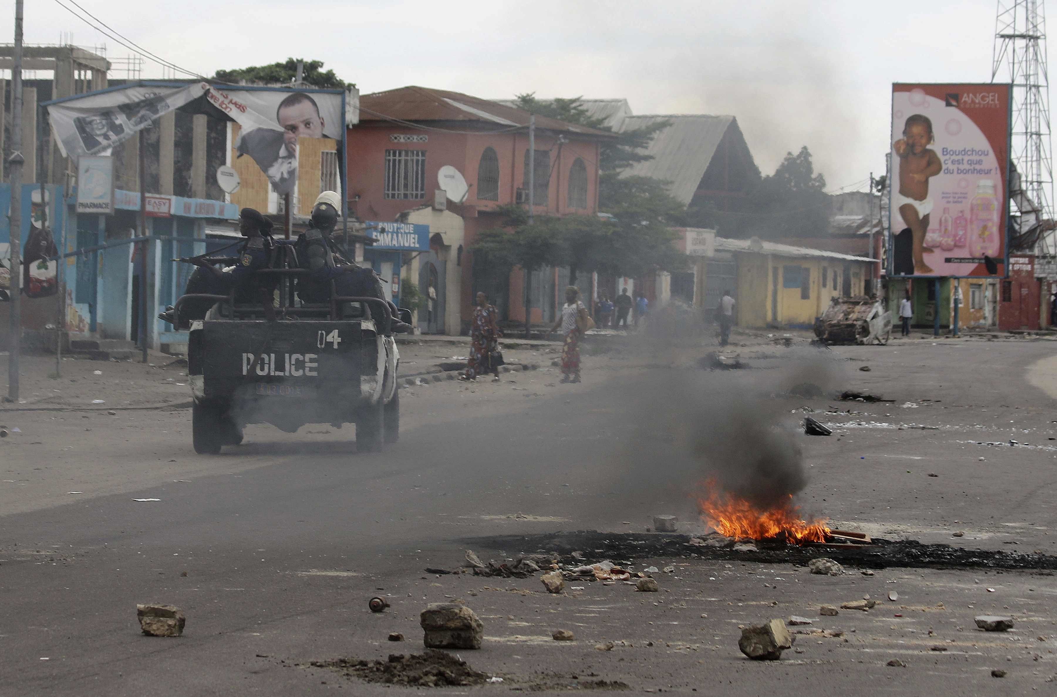 Policemen drive past burning debris during protests in Kinshasa, Democratic Republic of Congo, Tuesday, Dec. 20, 2016. (John Bompengo—AP)