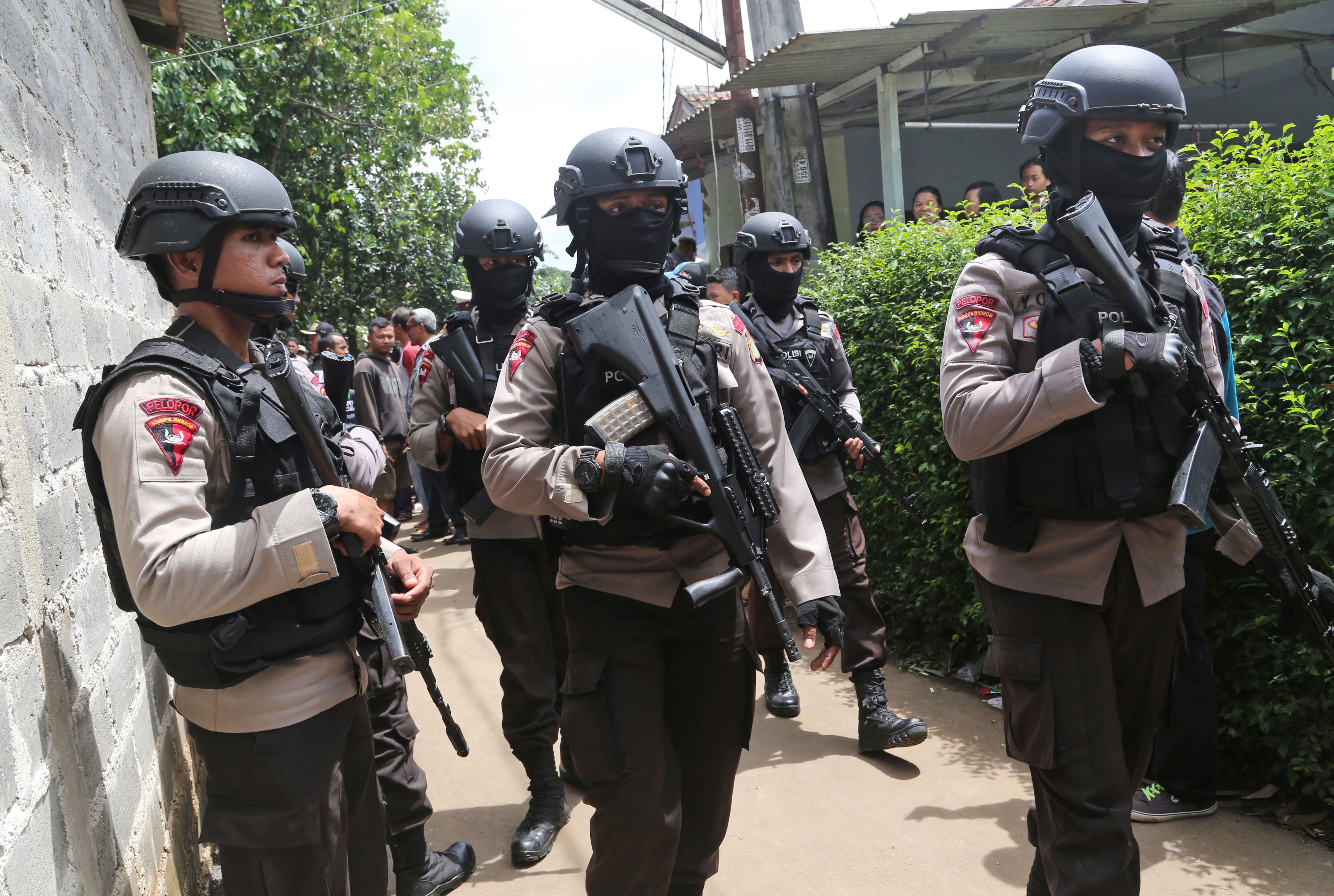 Police officers stand guard at a residential neighborhood in Tangerang, outside Jakarta, where police conducted a raid on a house used by suspected militants, on Dec. 21, 2016 (Tatan Syuflana—AP)
