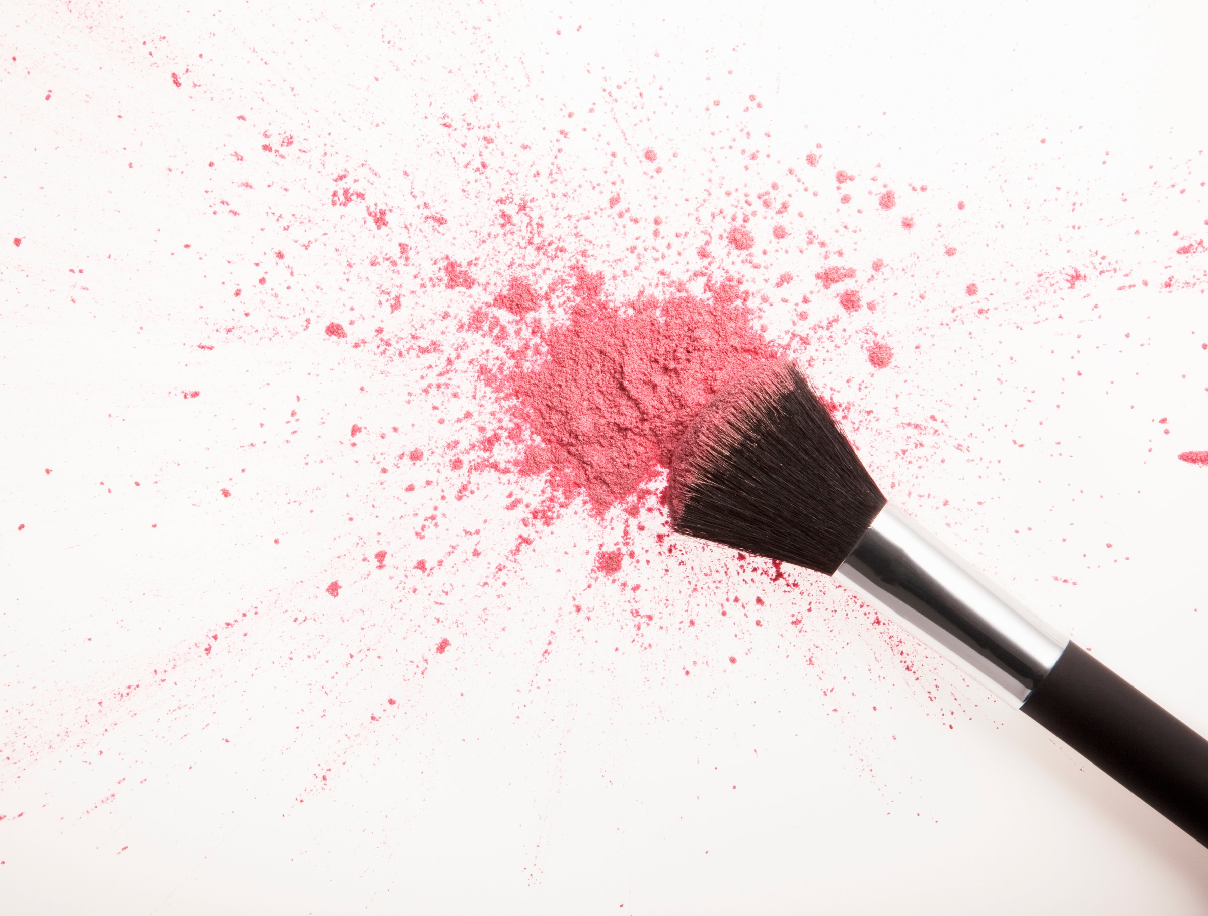 Makeup brush and pink blush powder splatter
