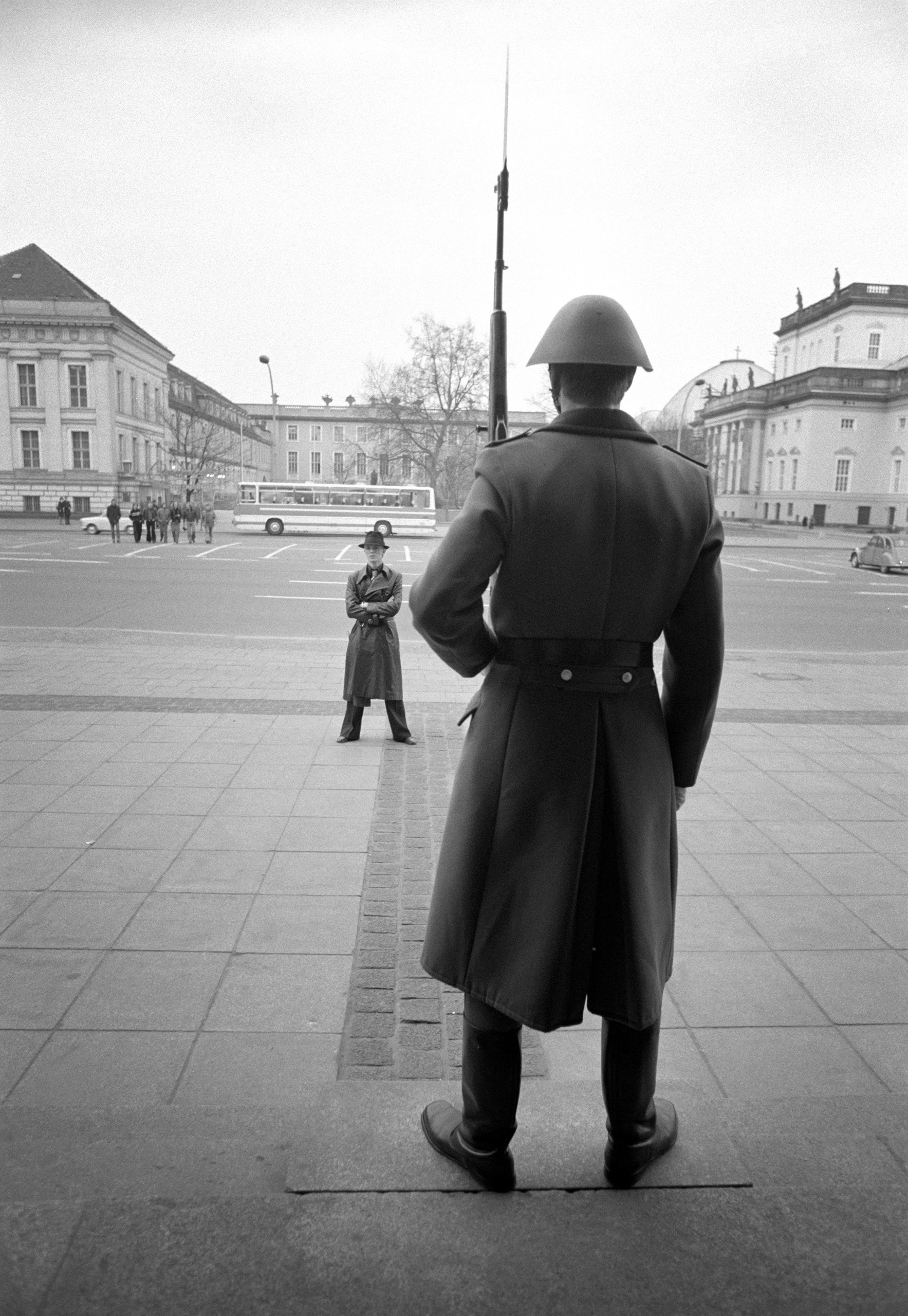 Bowie pauses in front of an armed guard, during a walk around East Berlin, 1976.