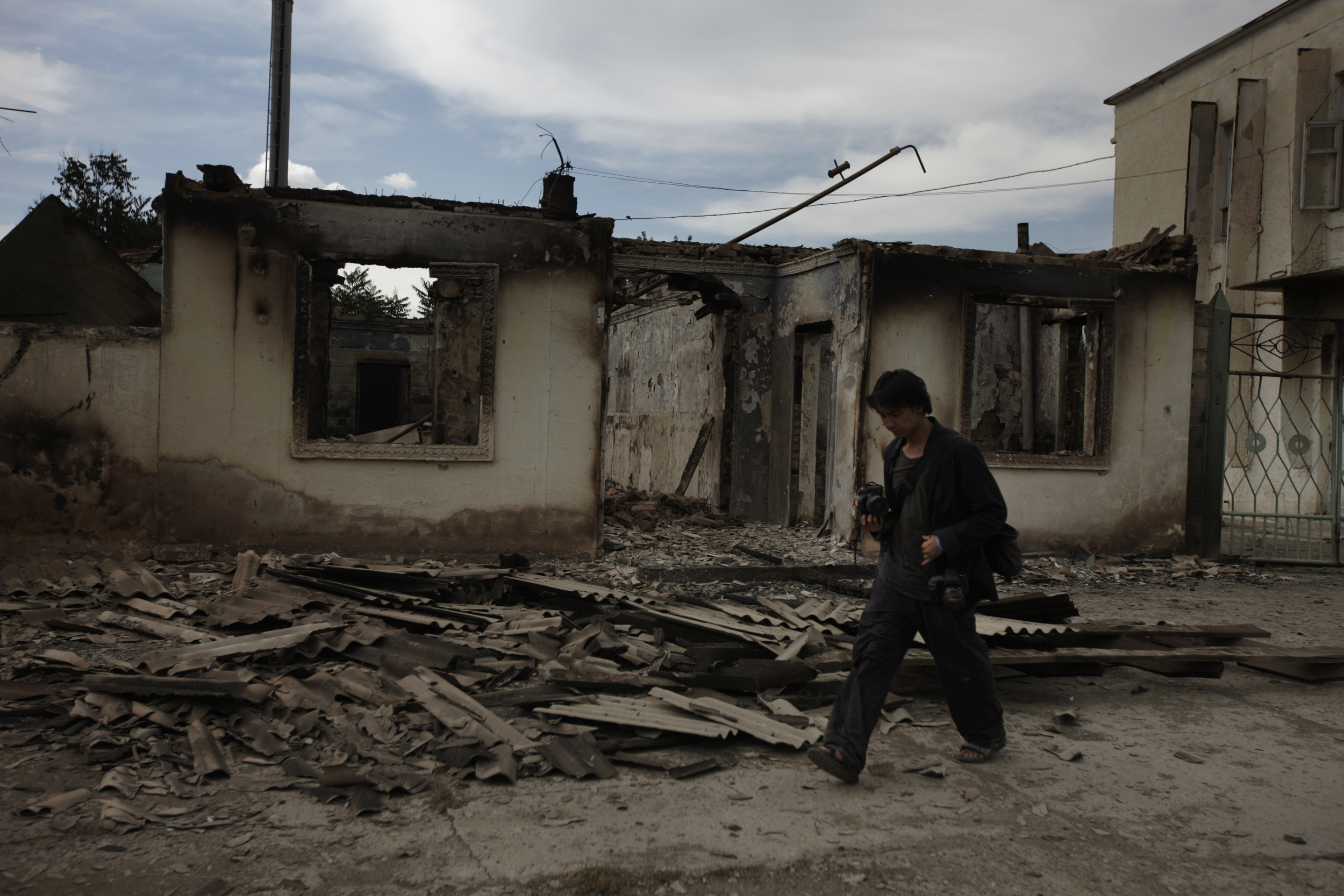 Ed Ou photographs a burned home after ethnic Kyrgyz mobs rampaged through minority Uzbek enclaves, burning homes and businesses in Shark, Kyrgyzstan. (Marina Gorobevskaya)