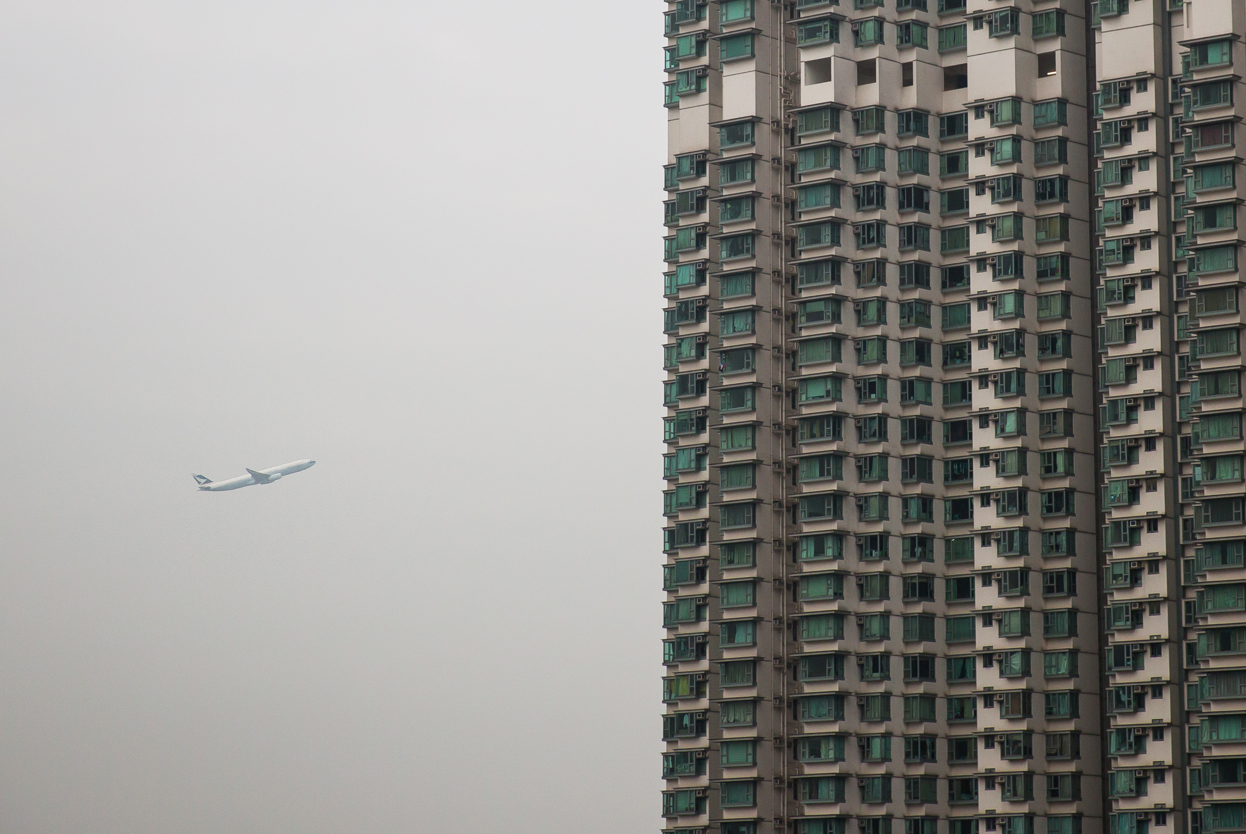 An aircraft flies past a residential building in the Tung Chung area of Hong Kong on Feb. 3, 2016 (Bloomberg/Getty Images)
