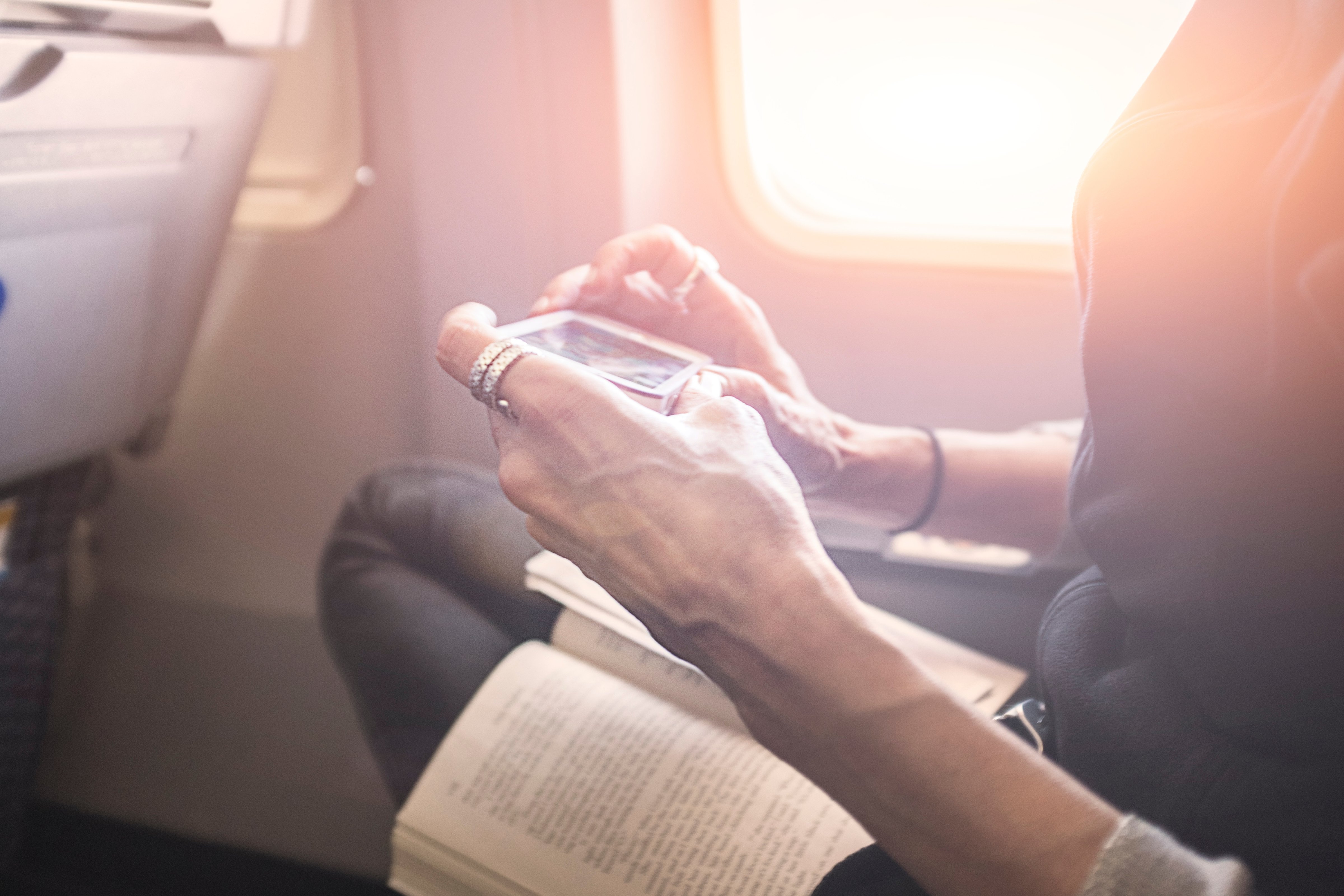 Person playing game on smartphone on board airplane
