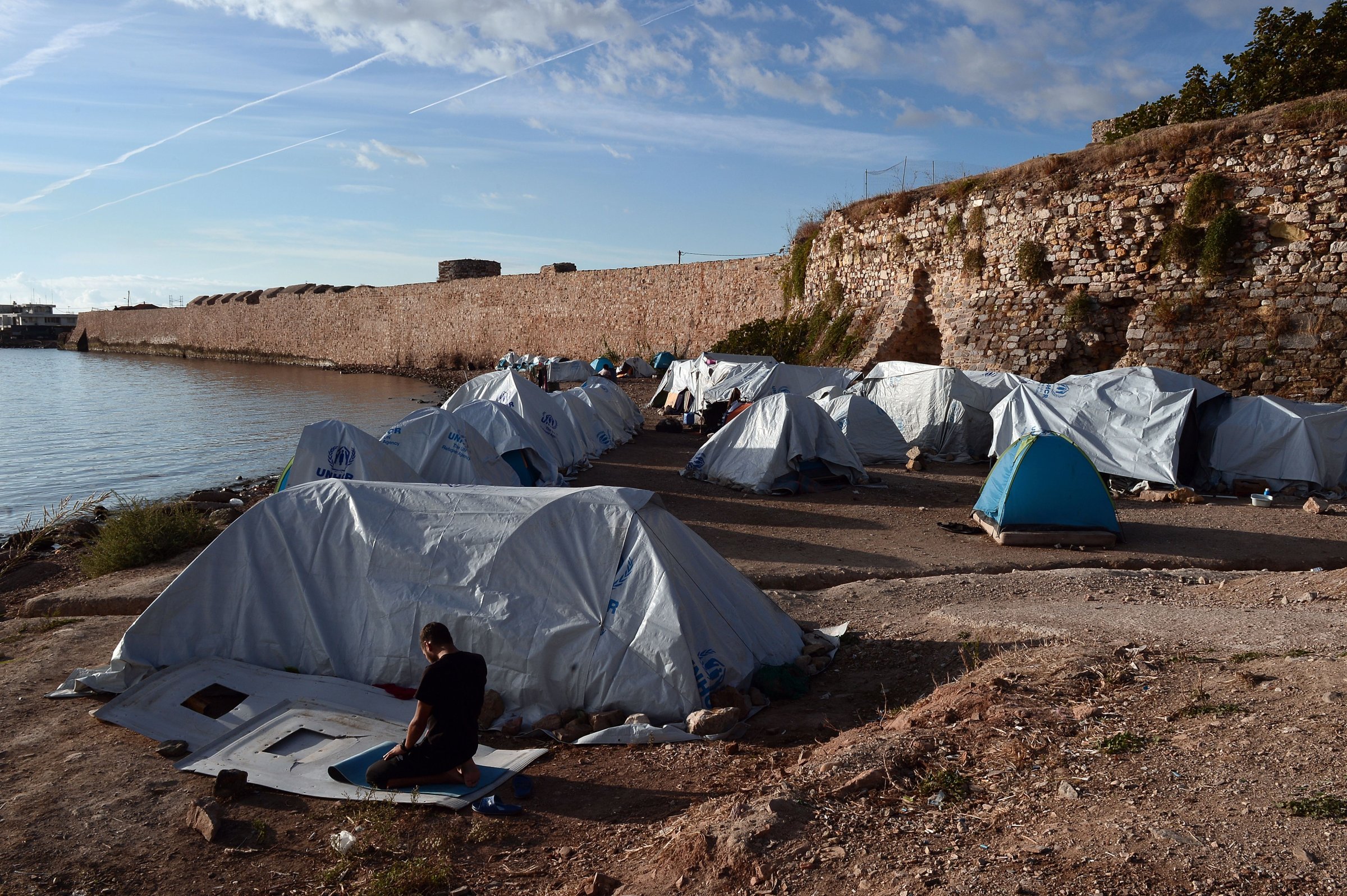 A man prays outside his tent set up on a beach at the Souda municipality-run refugee camp on the Greek island of Chios on October 13, 2016.