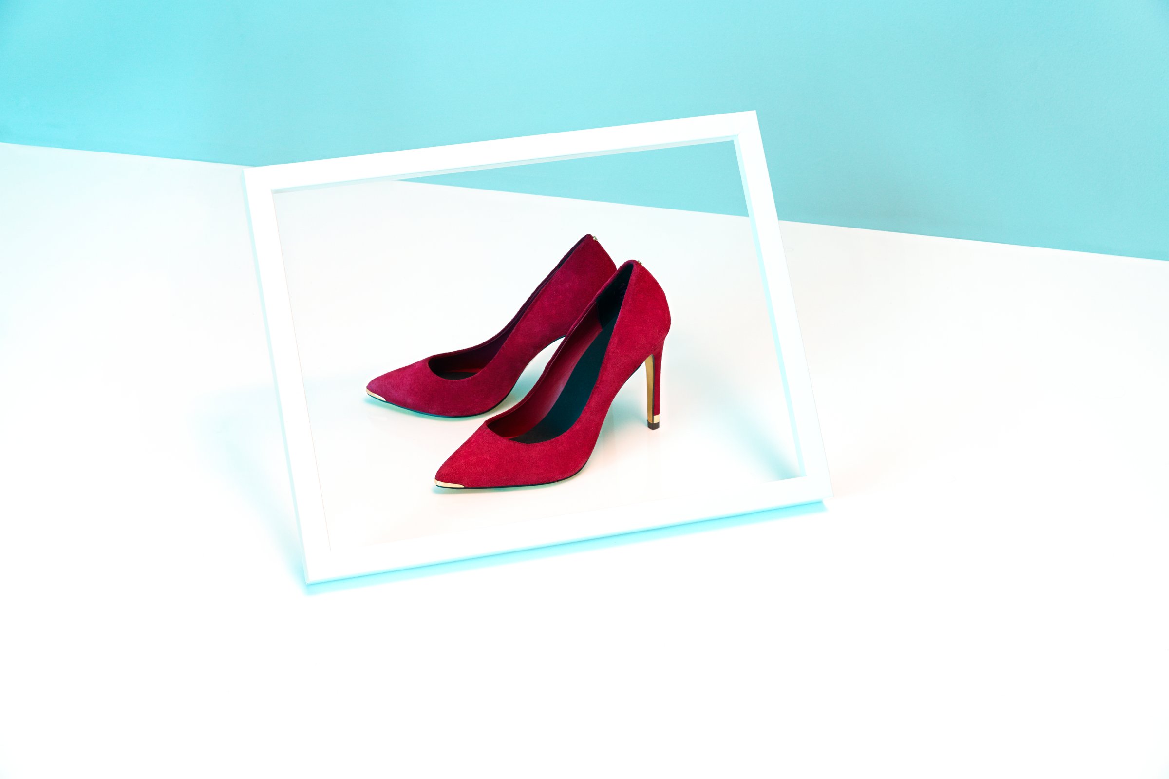 Pair of red high heeled shoes in a white frame