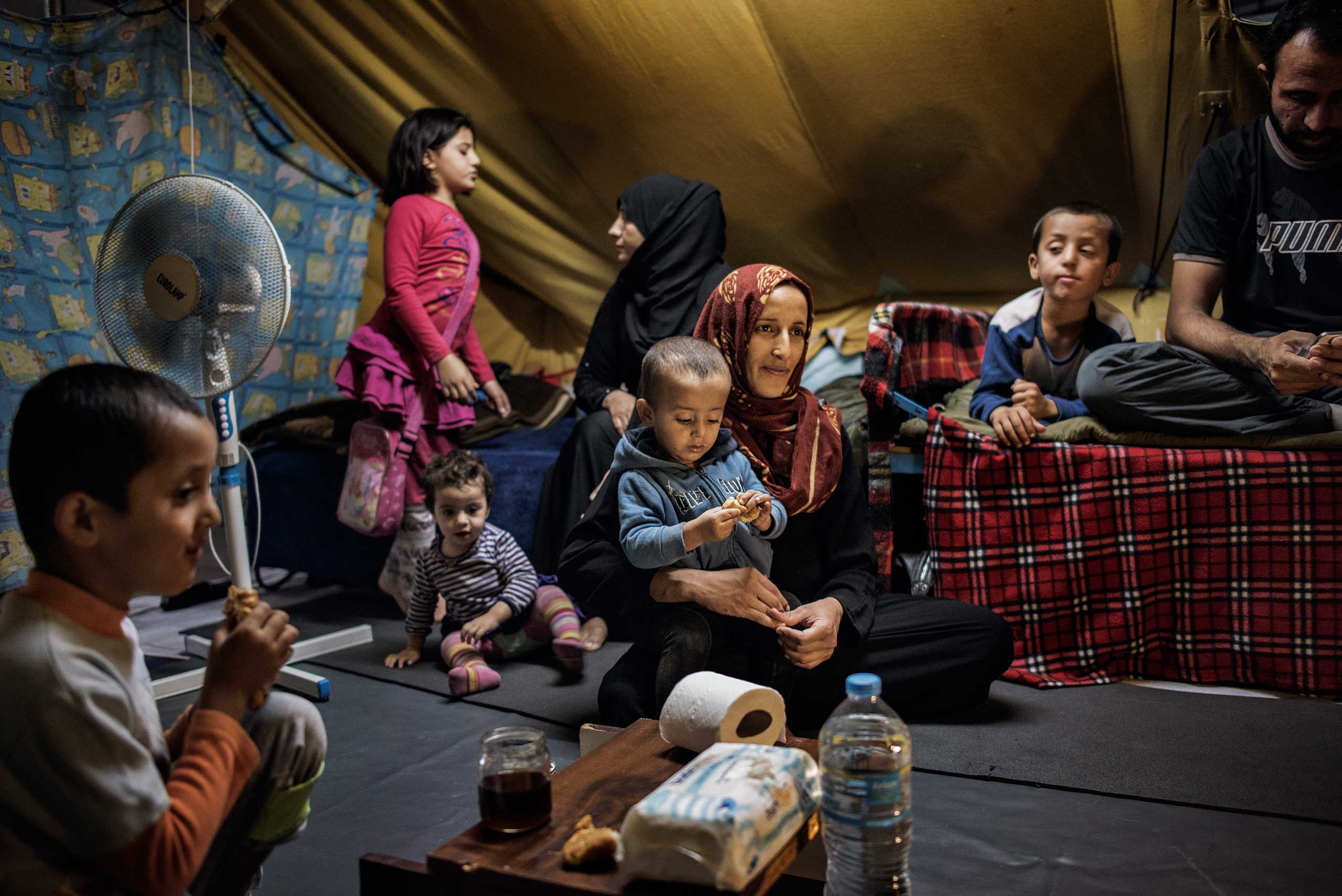 23-year-old Illham Alarabi, pregnant wither her fiifth son, sits with her children and husband, Minhel Alsaleh, 39, in their tent in the Oreokastro refugee camp in Thessaloniki, Greece, Sept. 8, 2016.