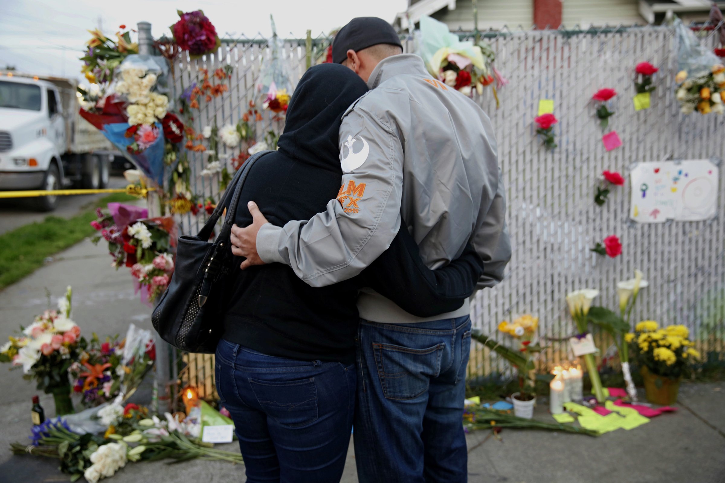 Mourners hug next to flowers near the site of the warehouse fire in Oakland, Calif., on Dec. 4, 2016.