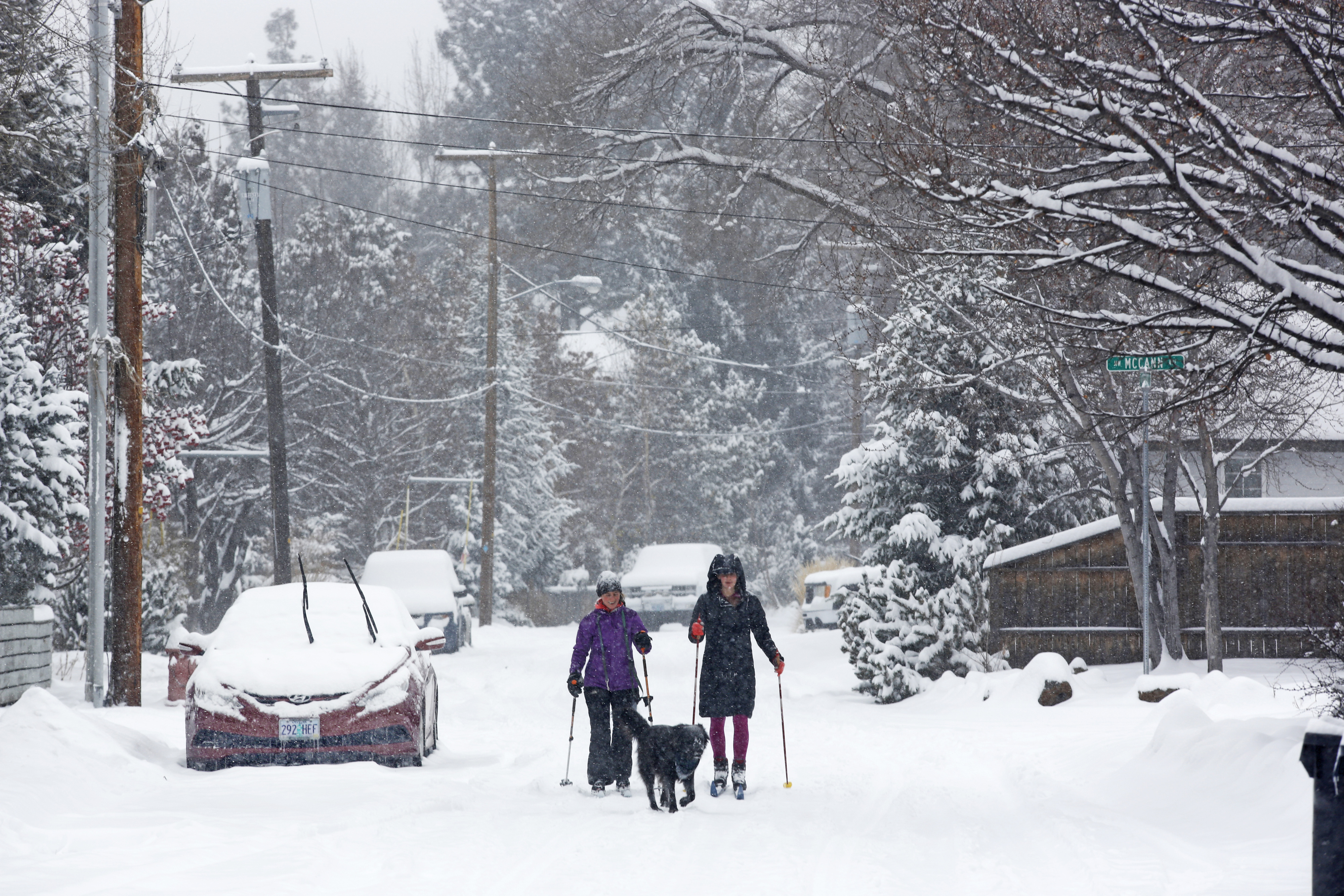 Anna Kaufman, left, and Hannah Rindlaub, right, ski down Riverfront Street in Bend, Ore., with their dog, Tula, during a winter storm on Dec. 8, 2016. (Jarod Opperman—The Bulletin/AP)