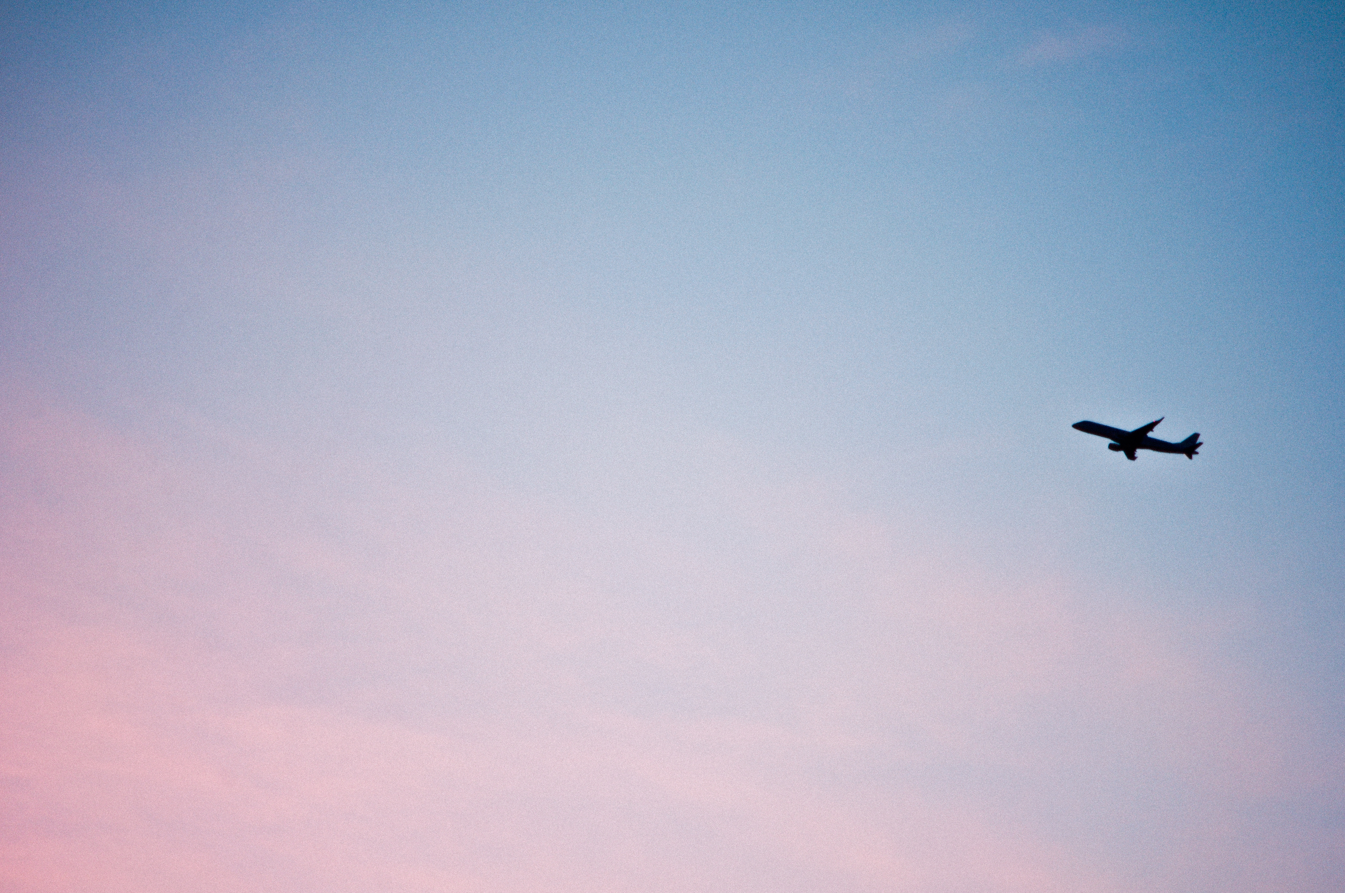 Low Angle View Of Airplane Flying In Sky At Sunset