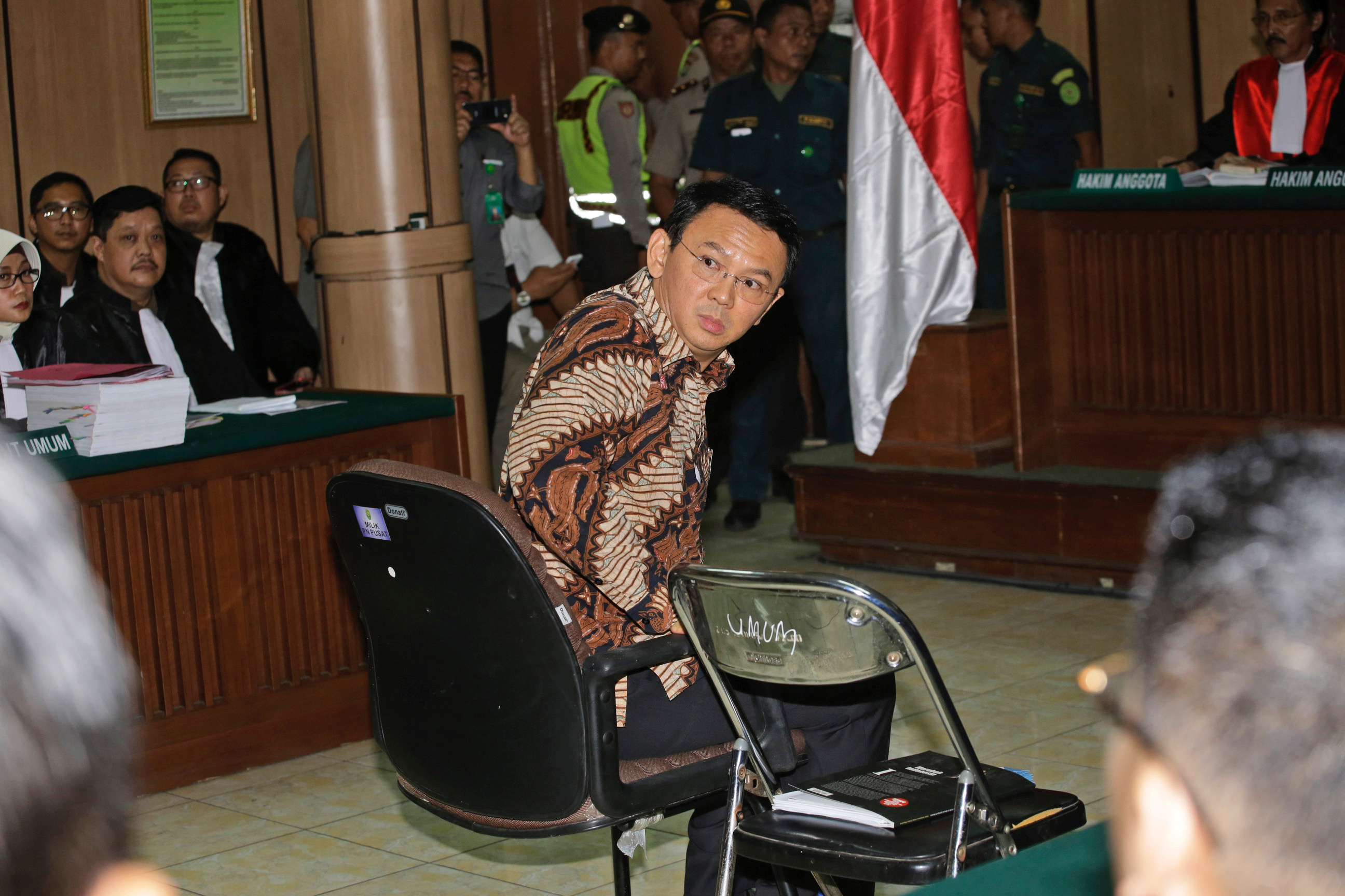 Gubernur Jakarta Basuki Tjahaja Purnama, lebih dikenal sebagai "Ahok", duduk di kursi terpidana saat sidang kasus penistaan agama mulai di Pengadilan Negeri Jakarta Utara, di Jakarta, pada tanggal 13 Desember 2016 (Pool—Reuters)