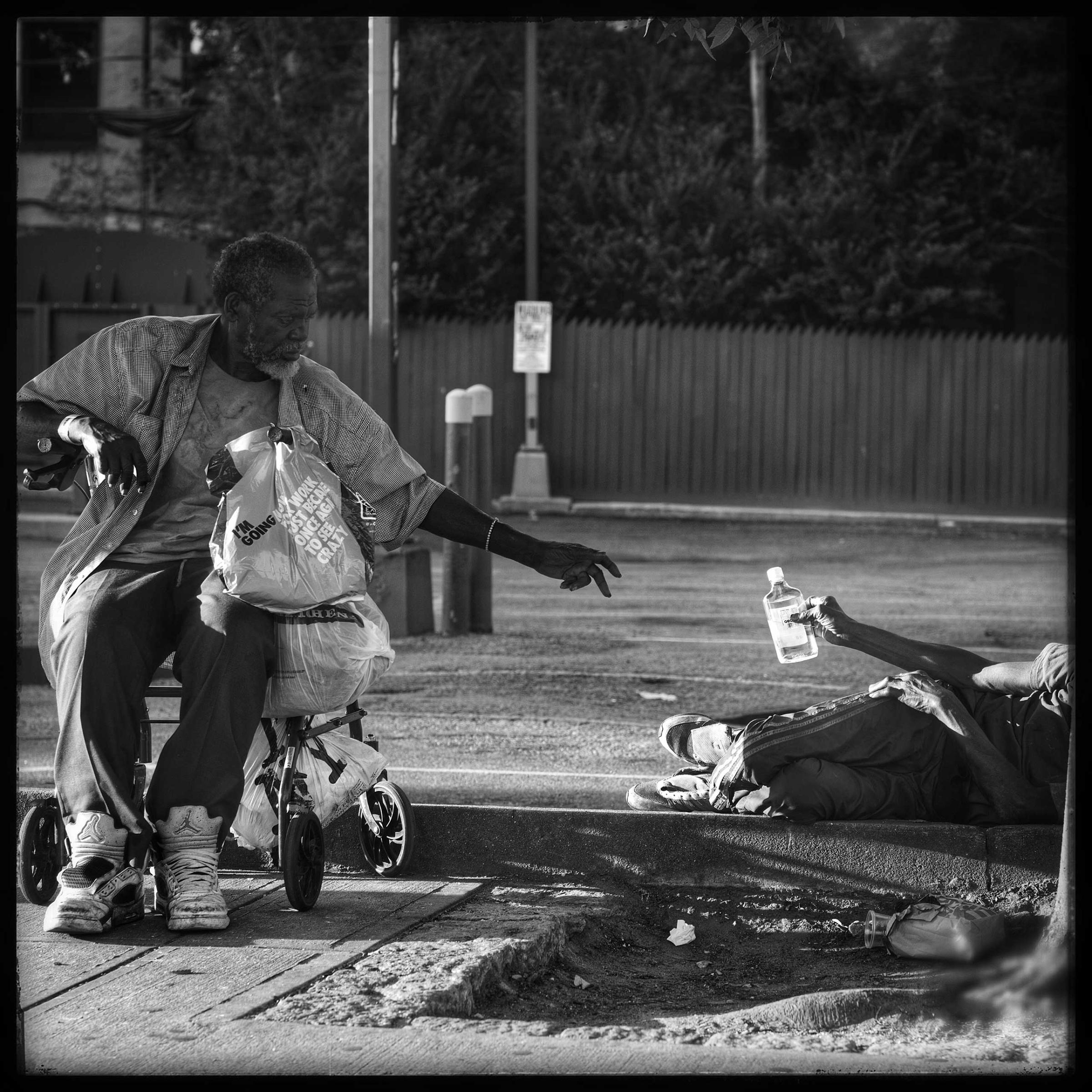 Sharing a drink with a friend. Two elderly gentlemen pass the time by drinking and sharing moments together on Fulton Street in Brooklyn.