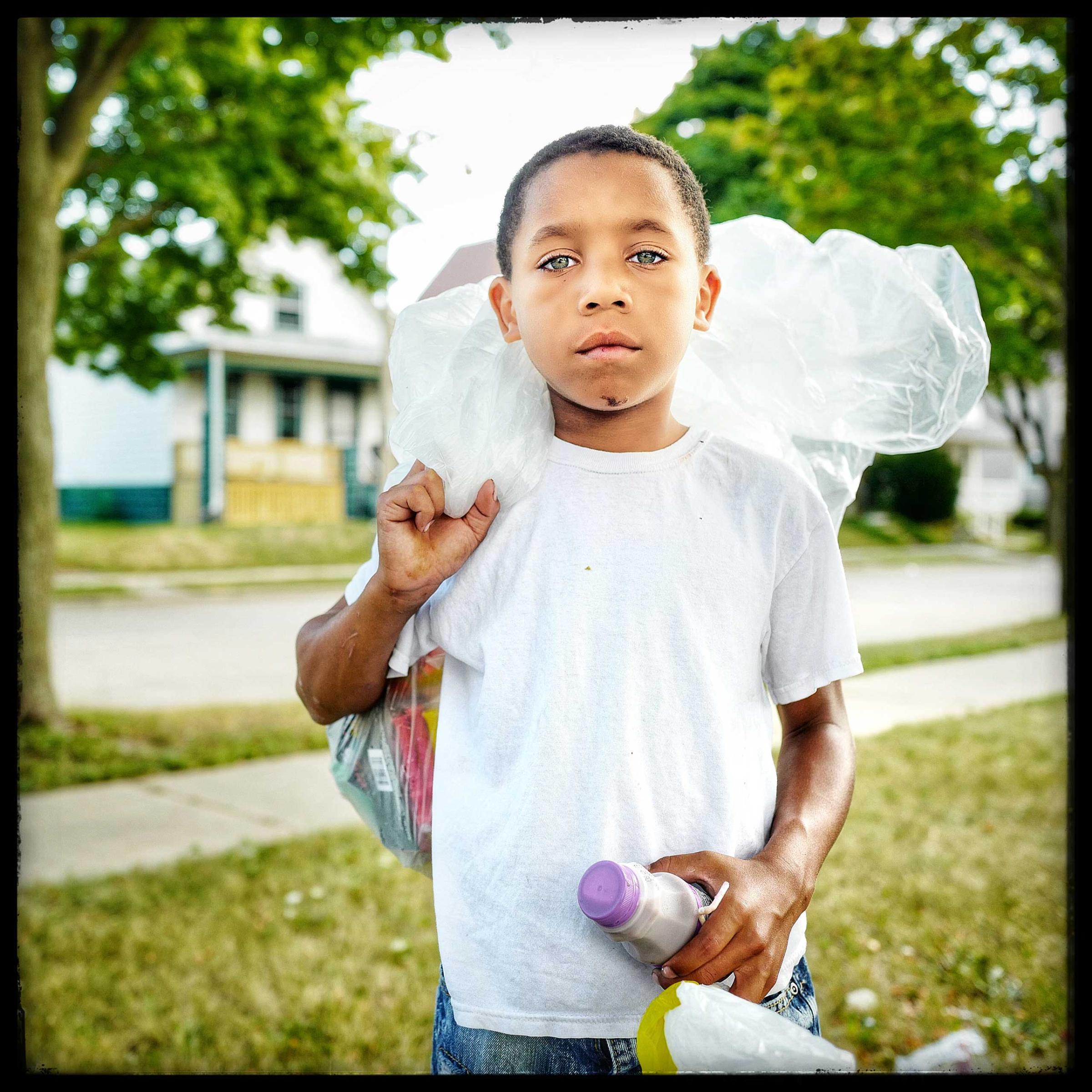 10 year old Darian after stopping at a Salvation army truck where he was given a ham sandwich, some fruits and a bottle of milk. Residents of the zipcode 53205 in Milwaukee often meet the truck around 1 pm where they are given a meal.