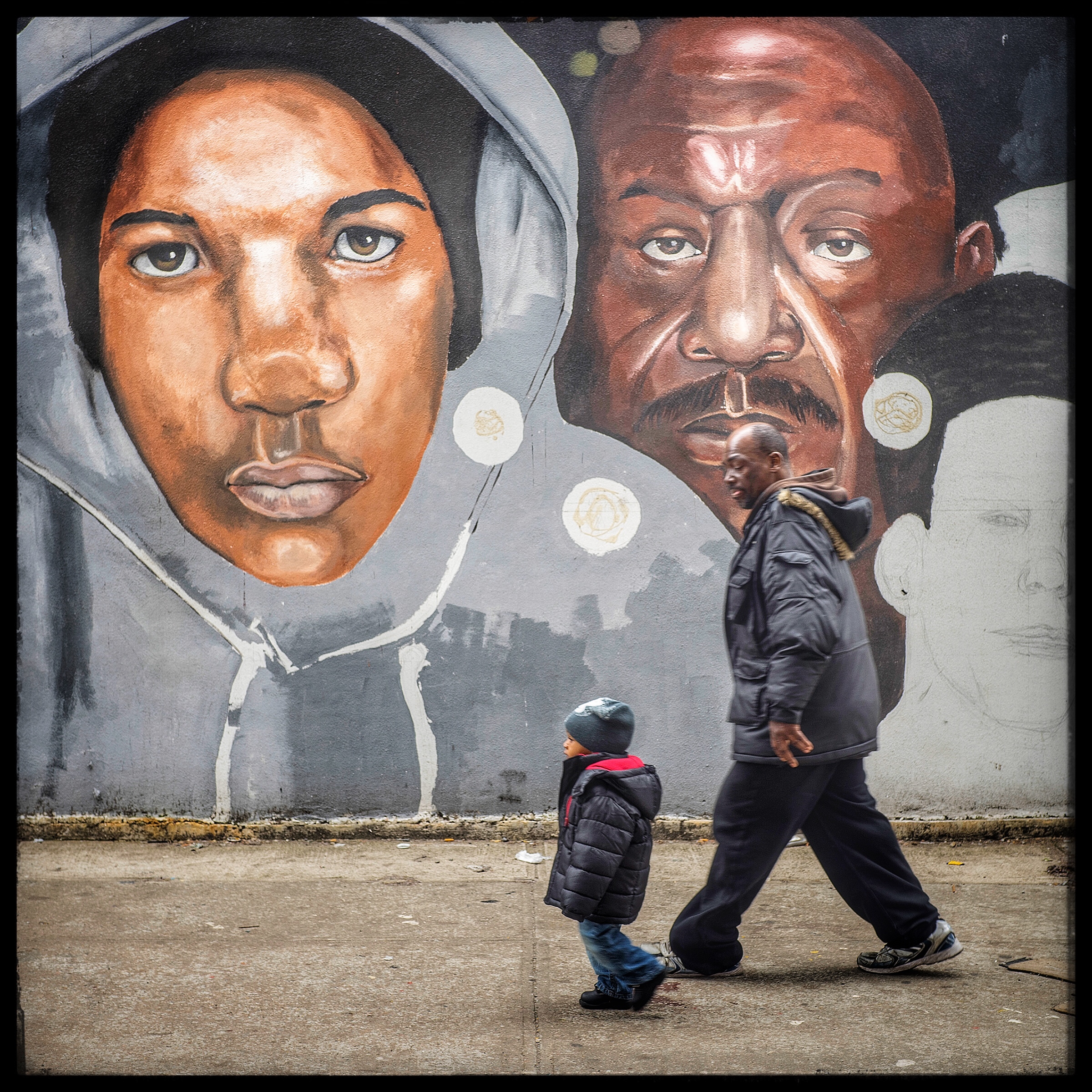 A father and son reflected against the portrait of Trayvon Martin's face on the mural in Brooklyn.