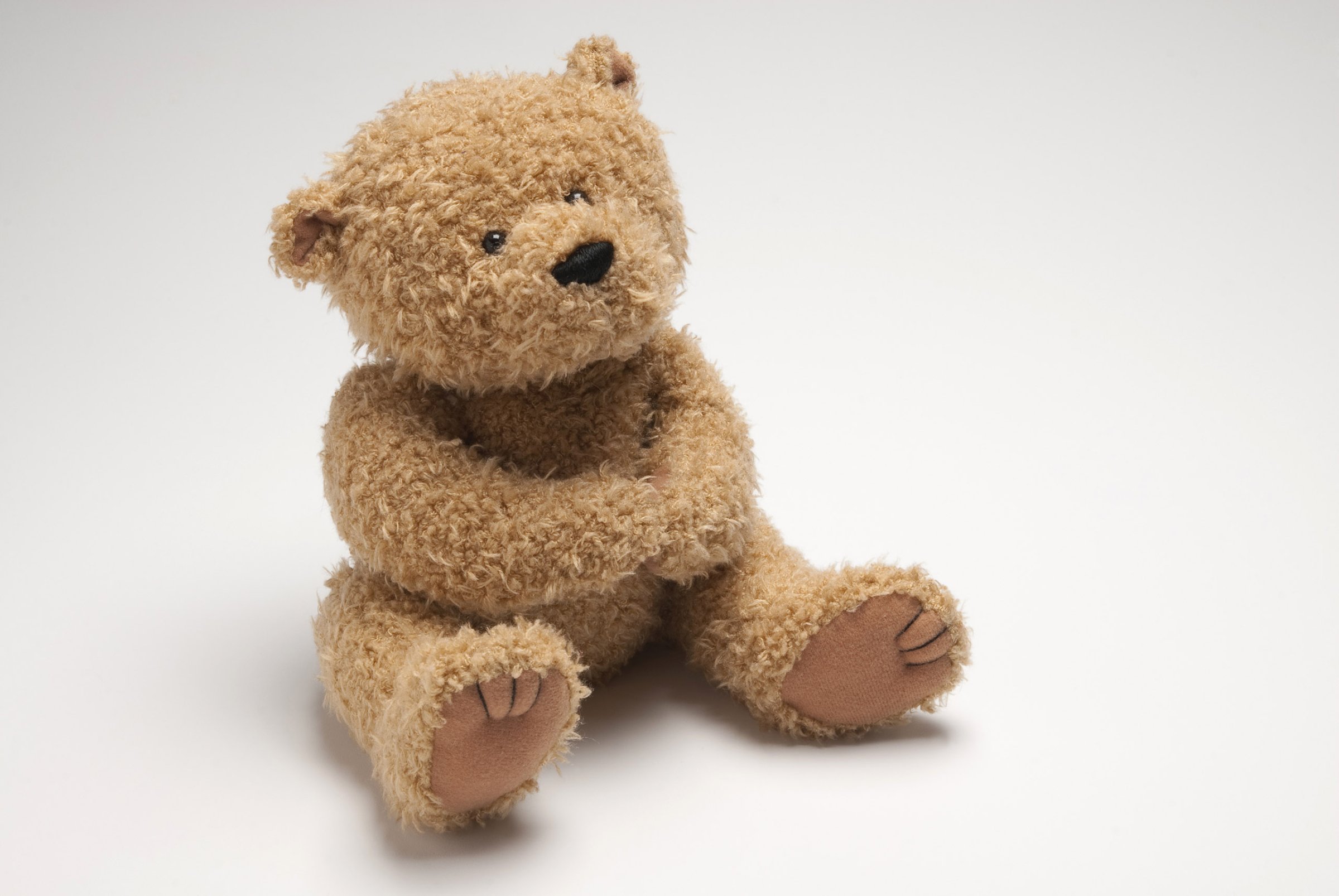 Light brown stuffed bear sitting on white surface