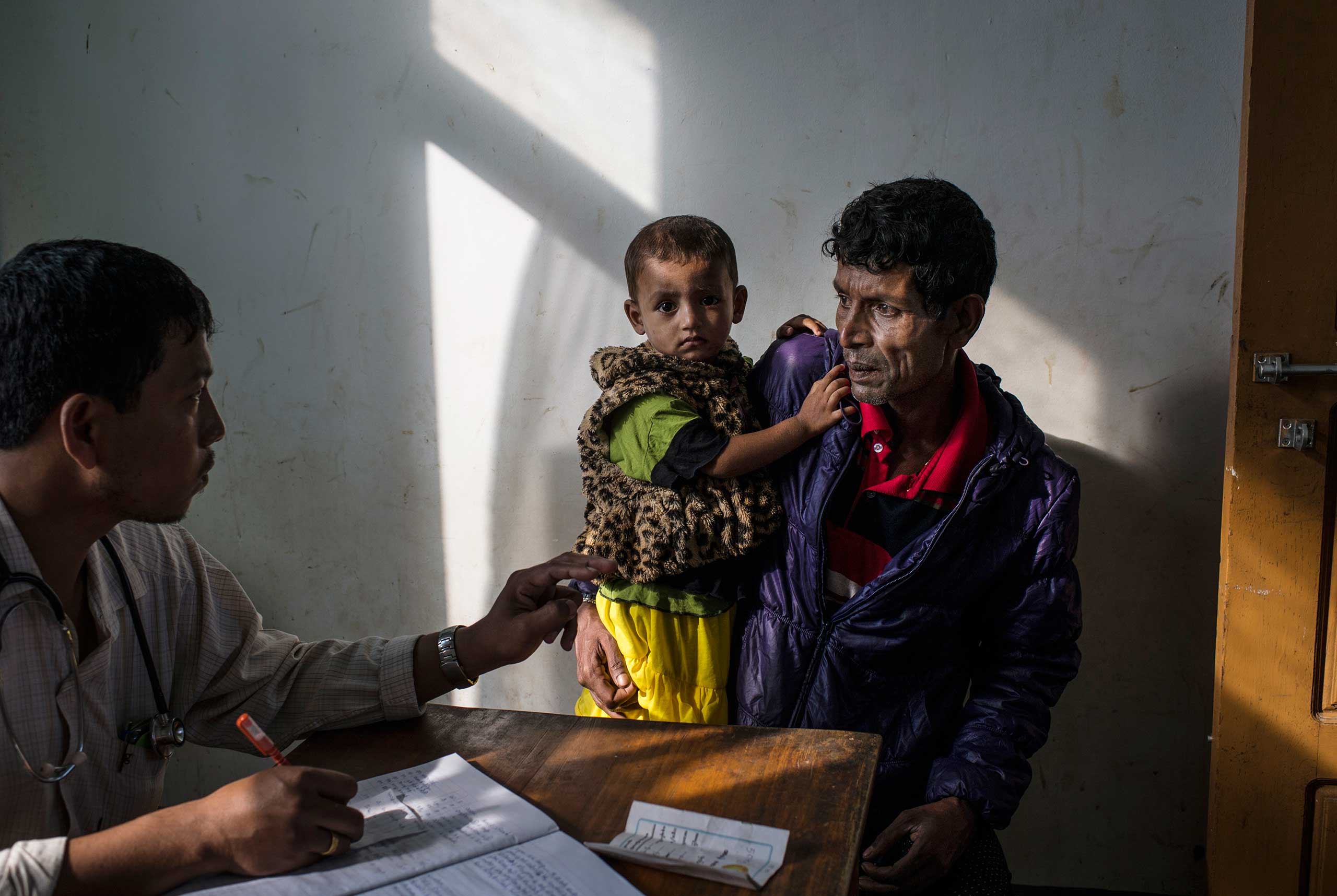 A government doctor looks over the sick child of a Rohingya man in the That Kay Pin Emergency Hospital in the camp for Internally Displaced Rohingya outside of Sittwe, in Myanmar, Nov. 25, 2015. The emergency hospital at That Kay Pin within the IDP camp has extremely limited resources, and doctors keep minimal hours to check and treat the ill or wounded.