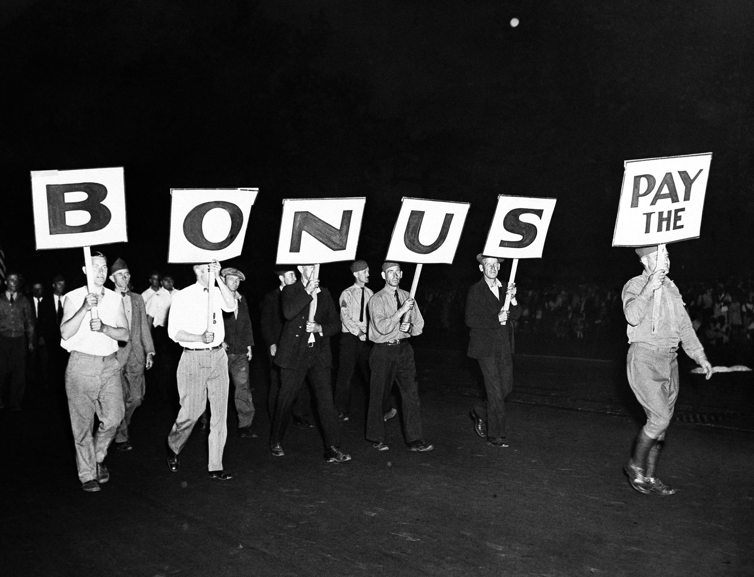 The "Pay The Bonus" sign carried by a group of world war veterans was typical of the banners with which the former soldiers who marched to Washington to press their demands for payments of the soldiers' bonus emphasized their point in the great parade they formed down Pennsylvania Avenue toward the capitol on the evening of June 7, 1932.