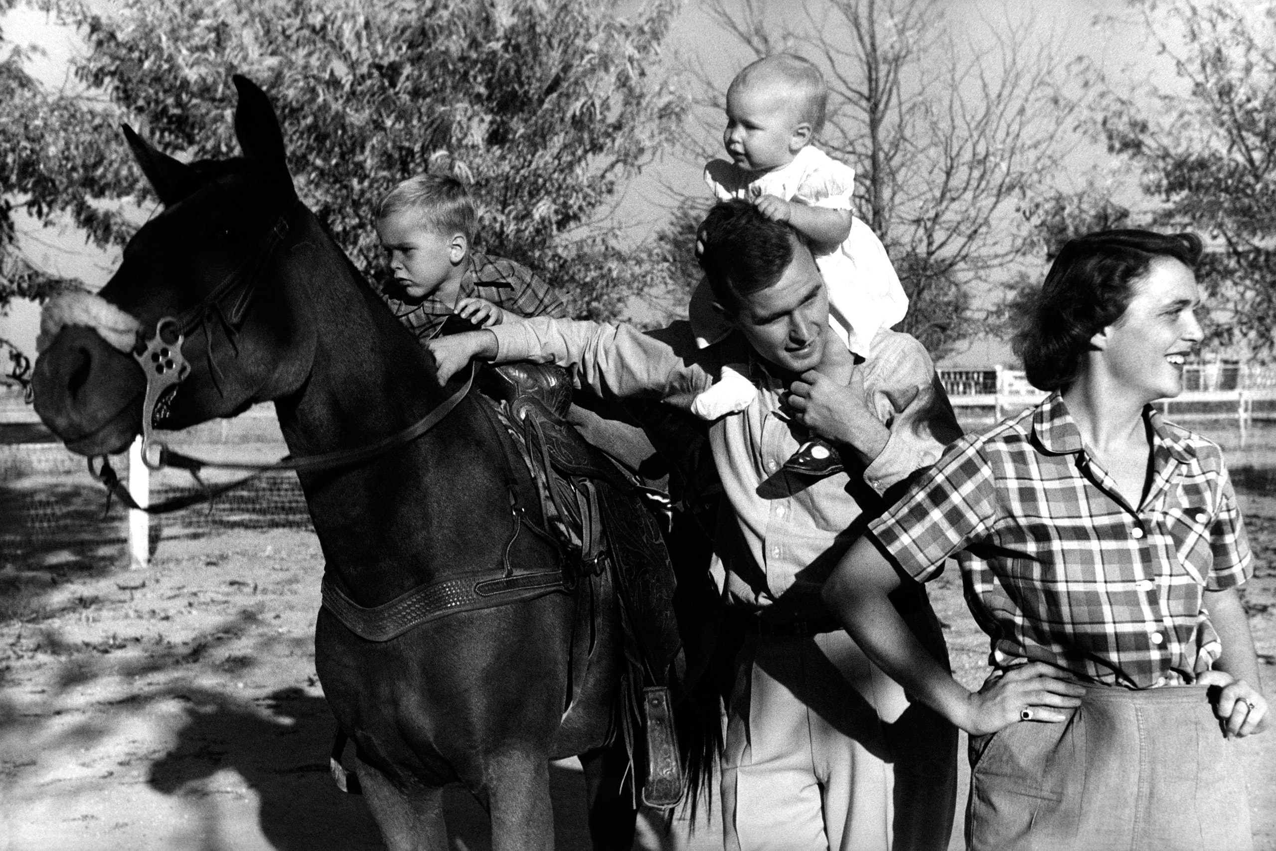 George H. W. Bush with his wife, Barbara with their children Pauline and George W. on horse in the yard of their Midland, Texas ranch, 1950.