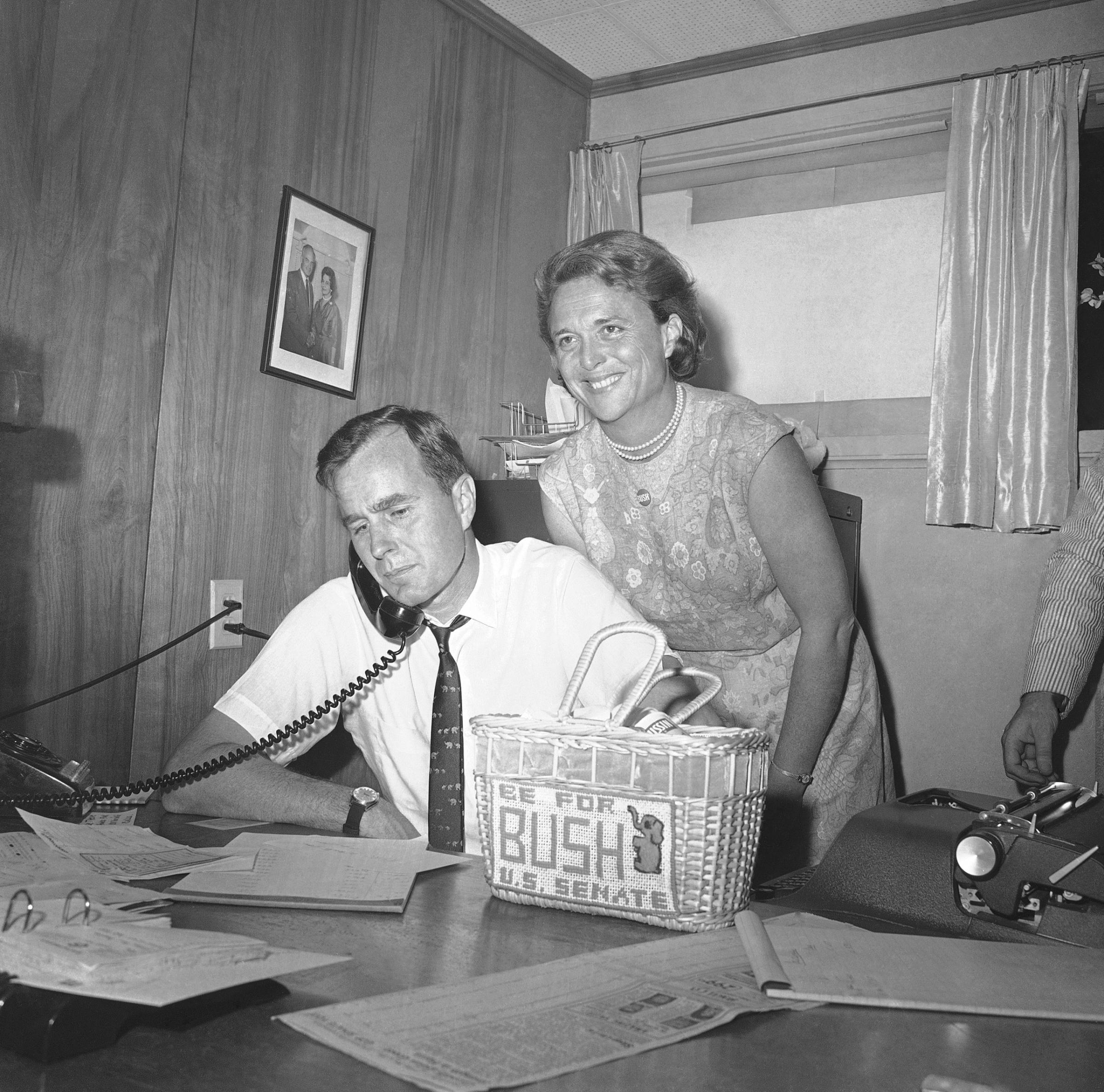 George H.W. Bush, candidate for the Republican nomination for the U.S. Senate, gets returns by phone at his headquarters in Houston, Saturday, June 6, 1964 as his wife Barbara, beams her pleasure at the news.