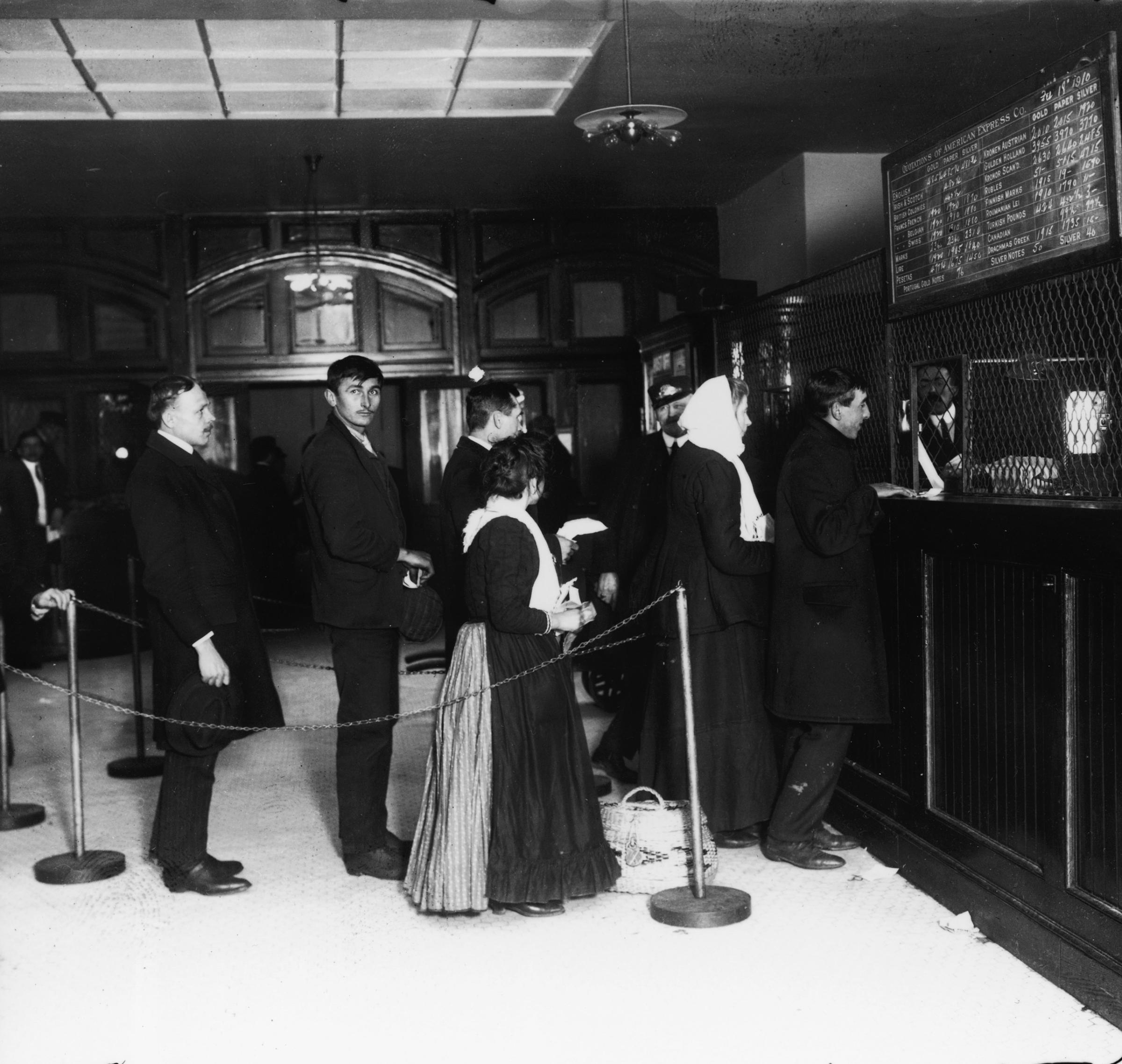 Customers wait in line at a teller's window at a bank on Ellis Island, New York, Feb. 18, 1910.