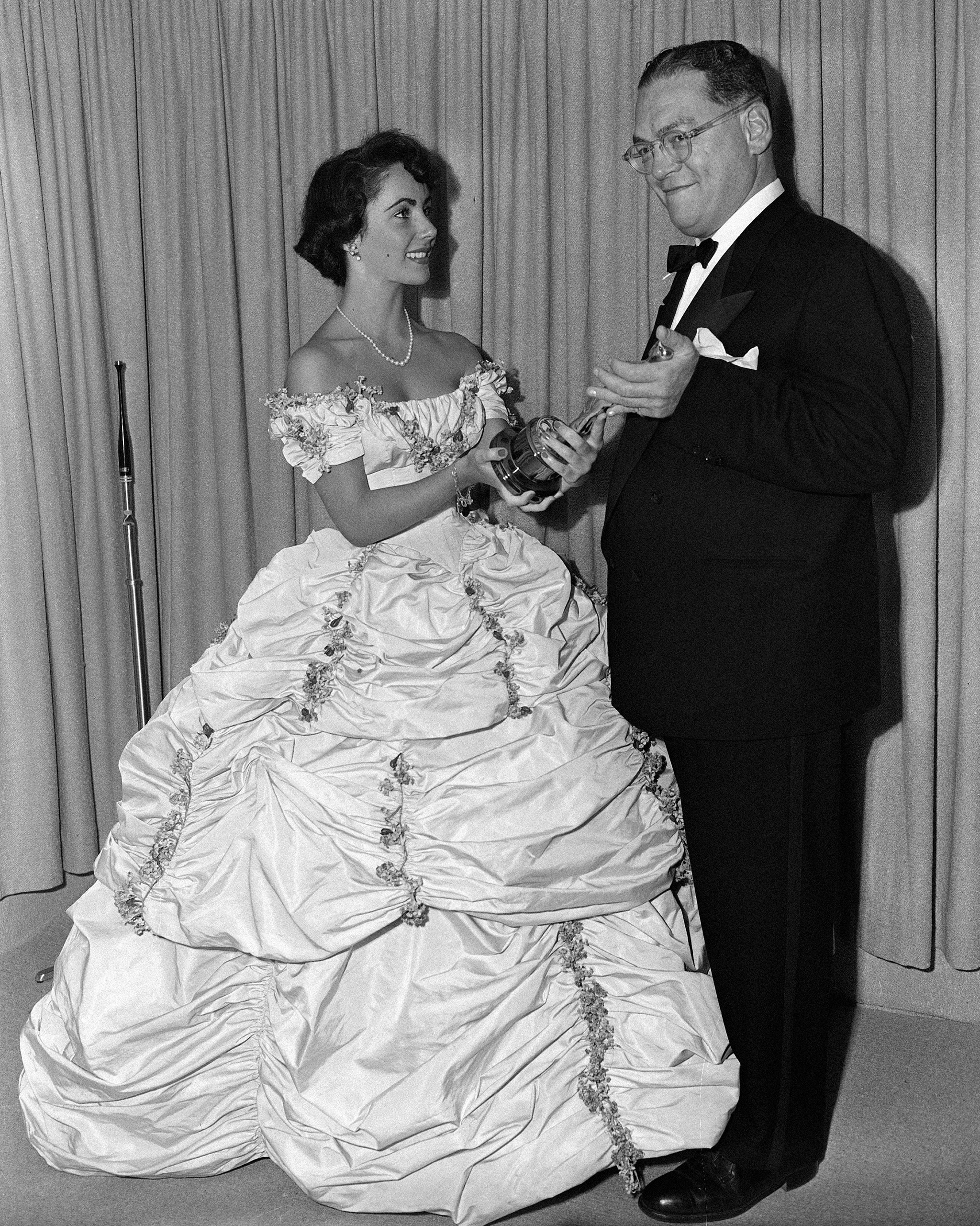 Elizabeth Taylor presents the Oscar for best costumes for black and white films to producer William Gordon of Universal-International at the Academy Awards, 1949.