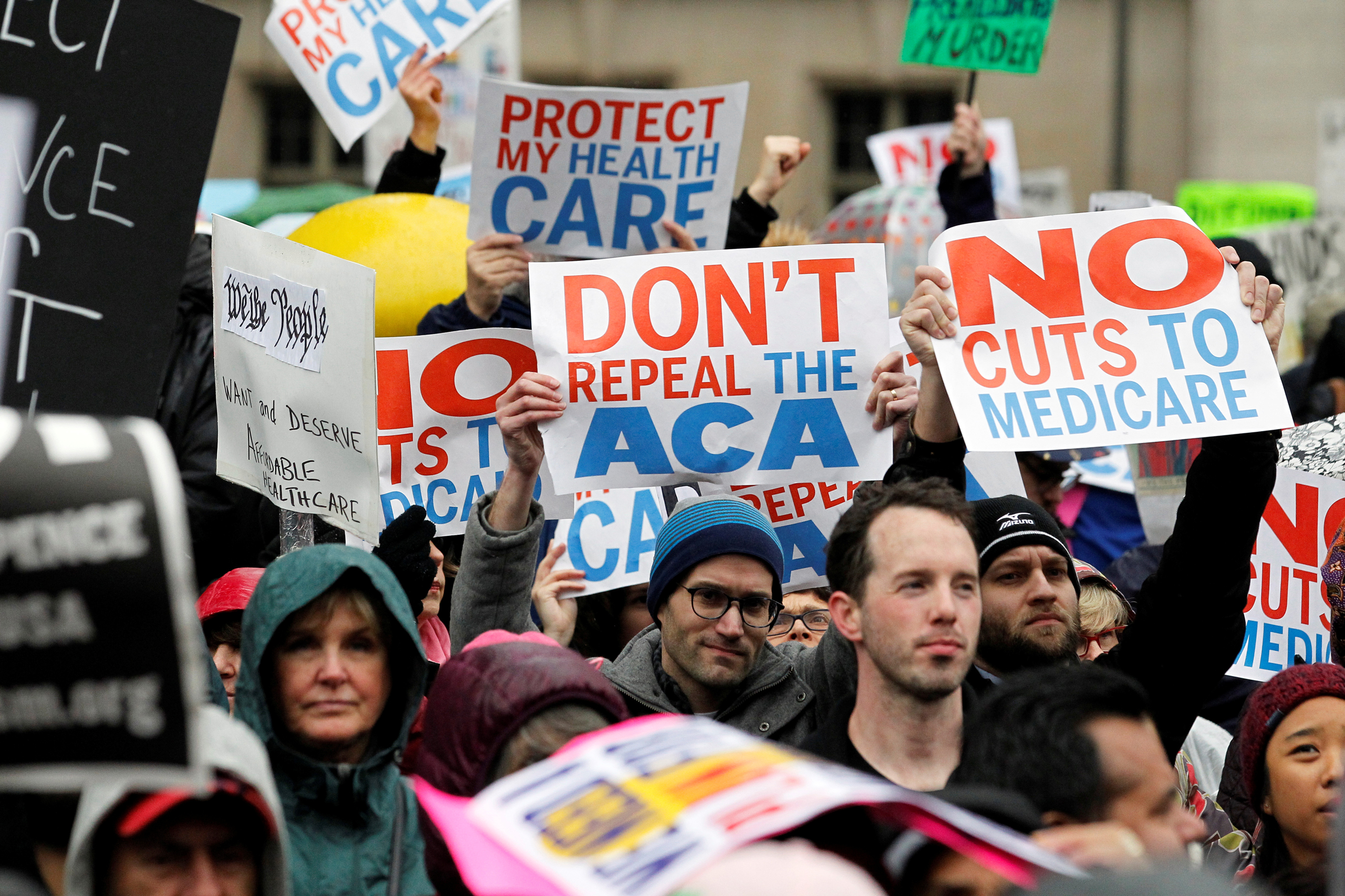 Demonstrators hold signs in support of the Affordable Care Act at a gathering before the start of a protest march near the hotel where House and Senate Republicans are attending a retreat in Philadelphia on Jan. 25, 2017. (Tom Mihalek—Reuters)