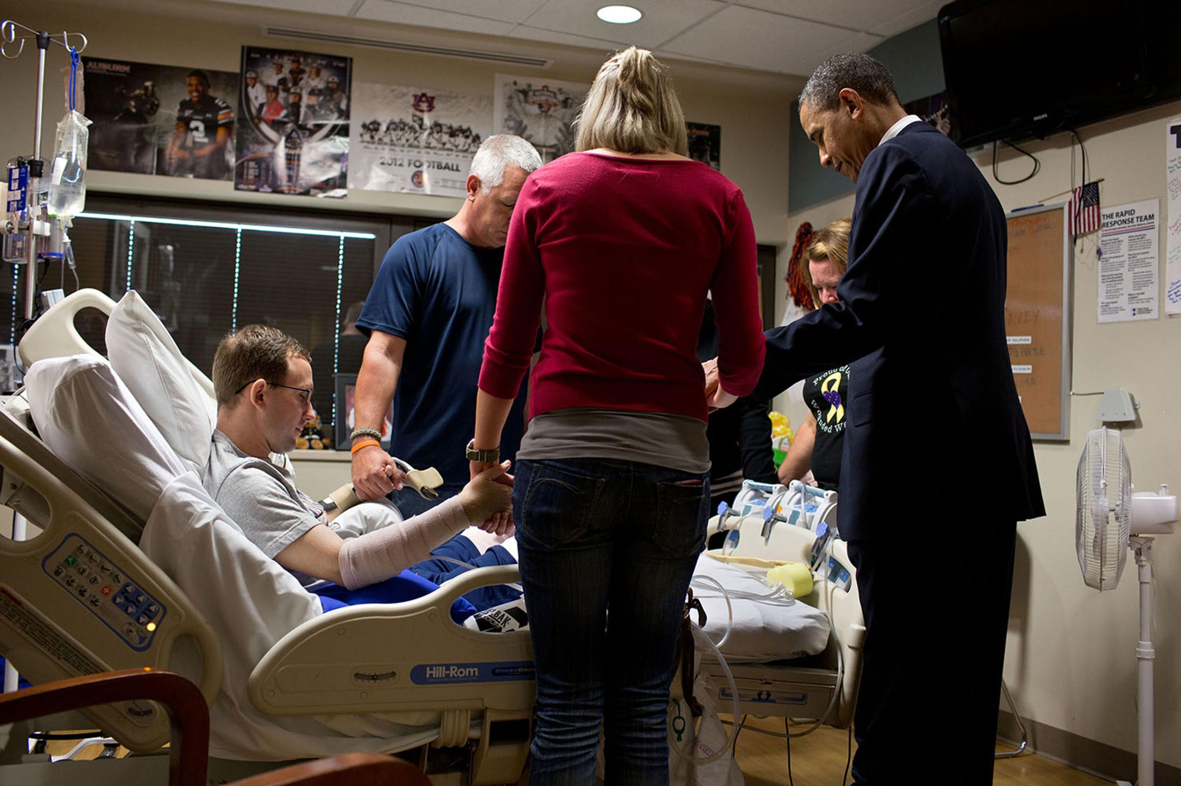 "The President prays with a wounded service member and his family during a visit to Walter Reed National Military Medical Center in Bethesda, Md. The President likes to make a few trips a year to Walter Reed to visit wounded warriors and their families,"June 28, 2012.