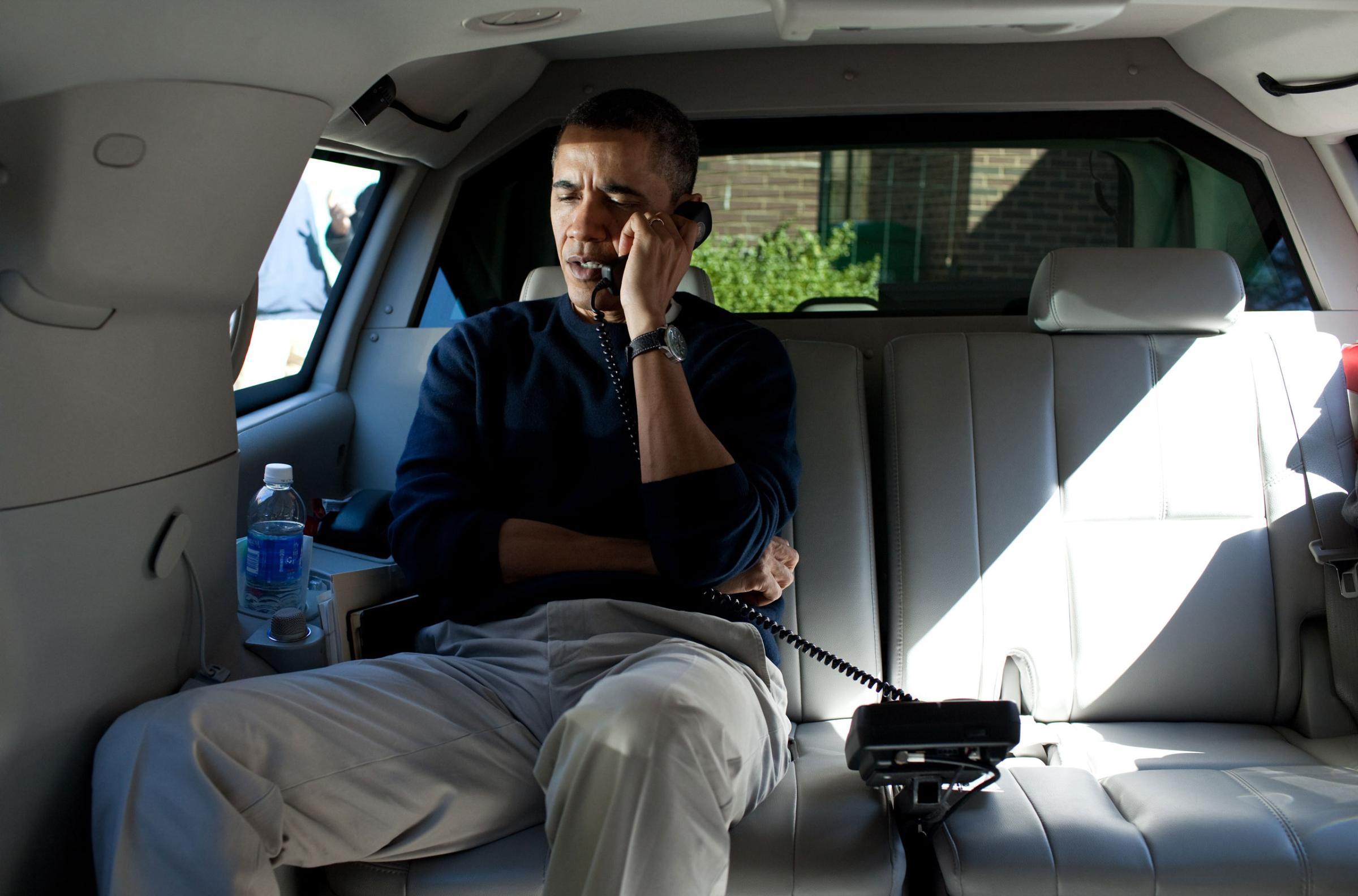 President Barack Obama talks on the phone with Afghanistan President Hamid Karzai from his vehicle outside the Jane E. Lawton Community Center in Chevy Chase, Maryland, Sunday, March 11, 2012.