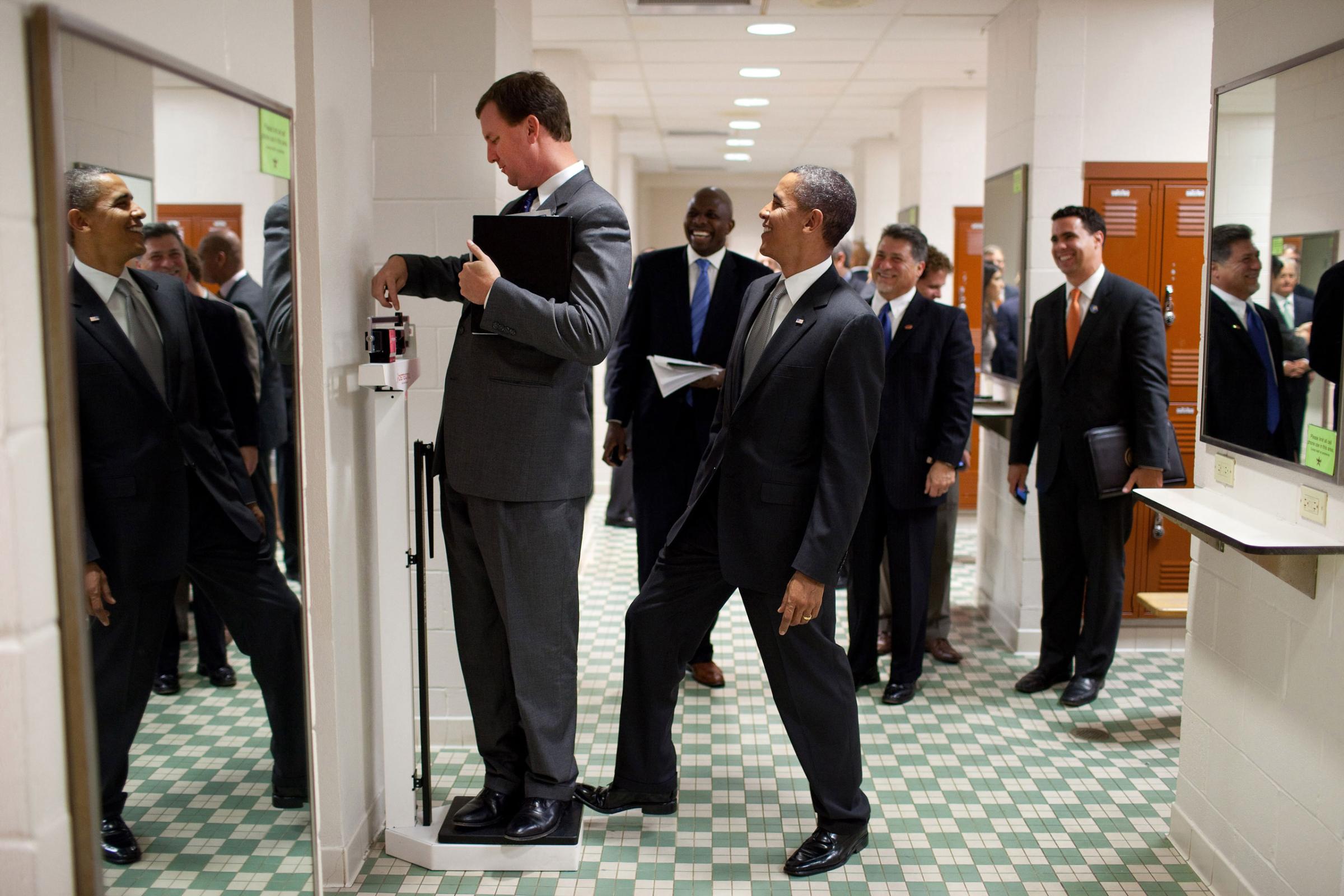 President Barack Obama puts his toe on the scale as Trip Director Marvin Nicholson tries to weigh himself during a hold in the volleyball locker room at the University of Texas in Austin, Texas, Aug. 9, 2010.
